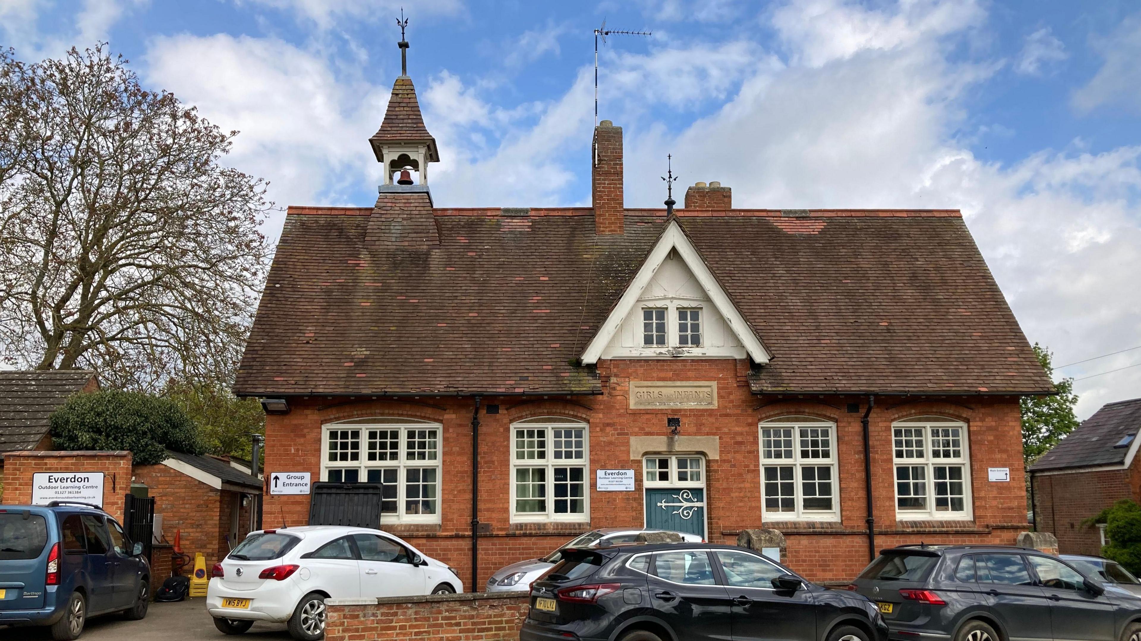 Victorian single-storey school building with cars parked in front