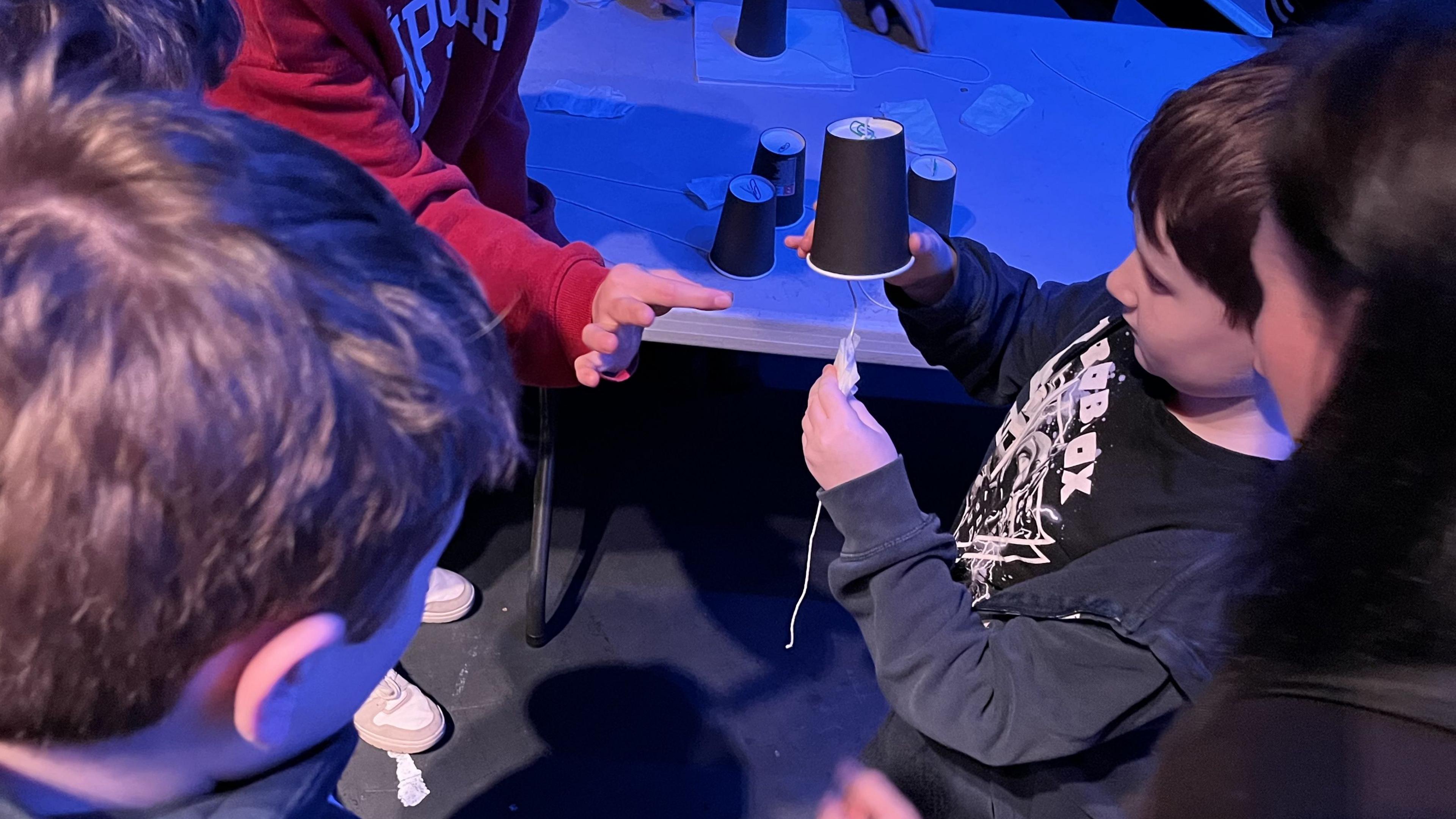 Children making different noises using cups and string