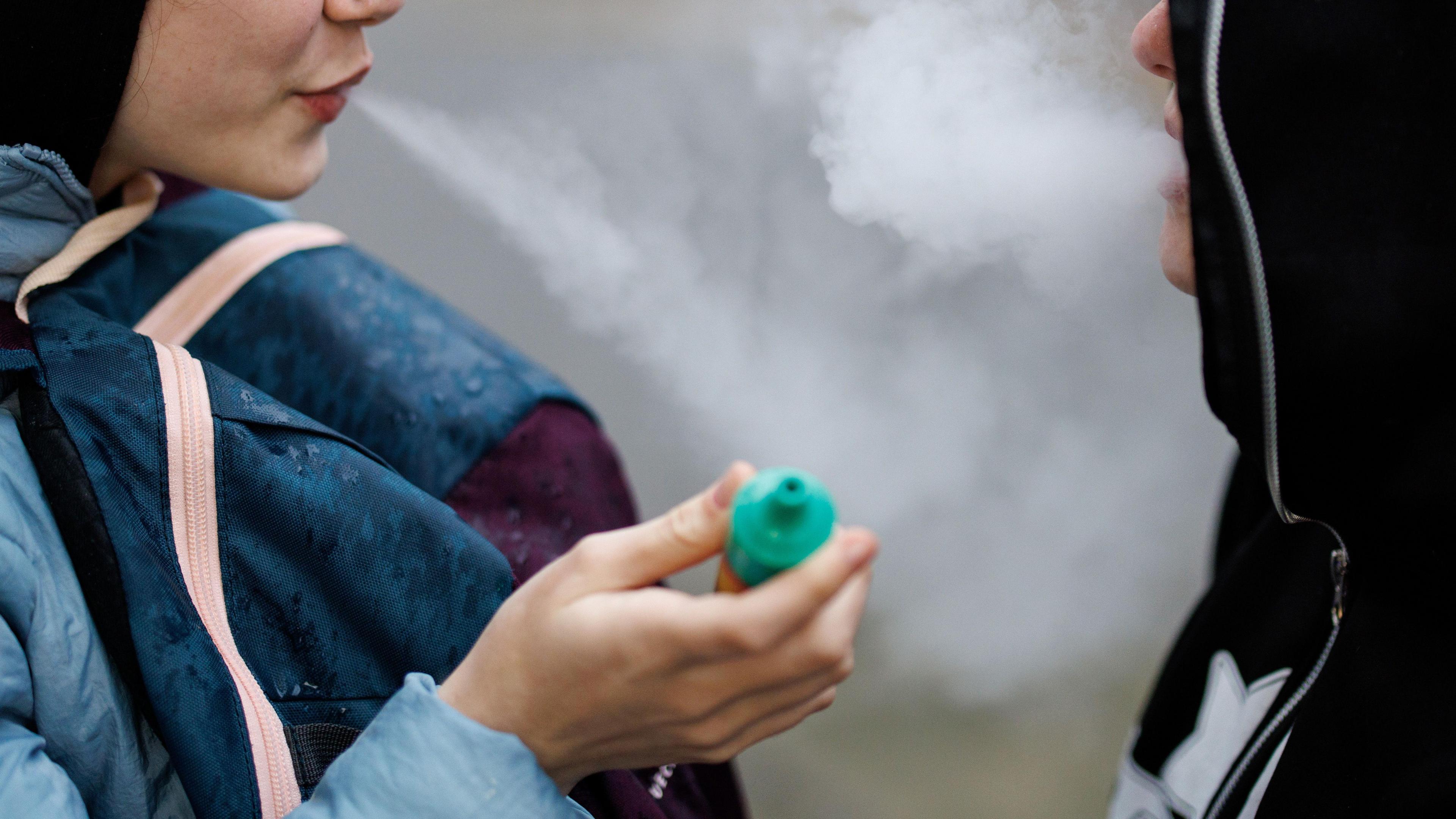 Two young people using vaping products