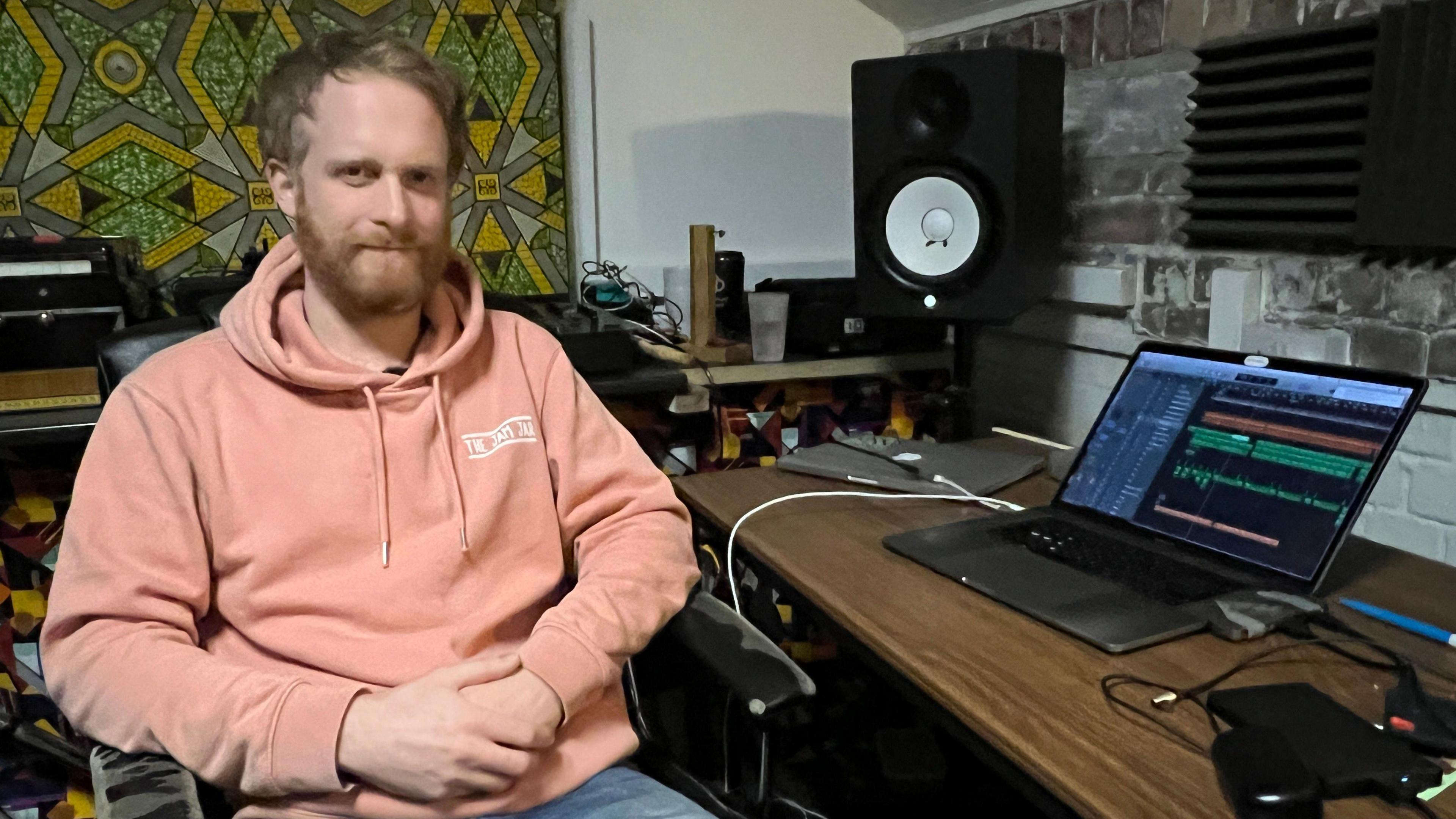 Tristan Shaw in a pink hoodie sitting at his desk