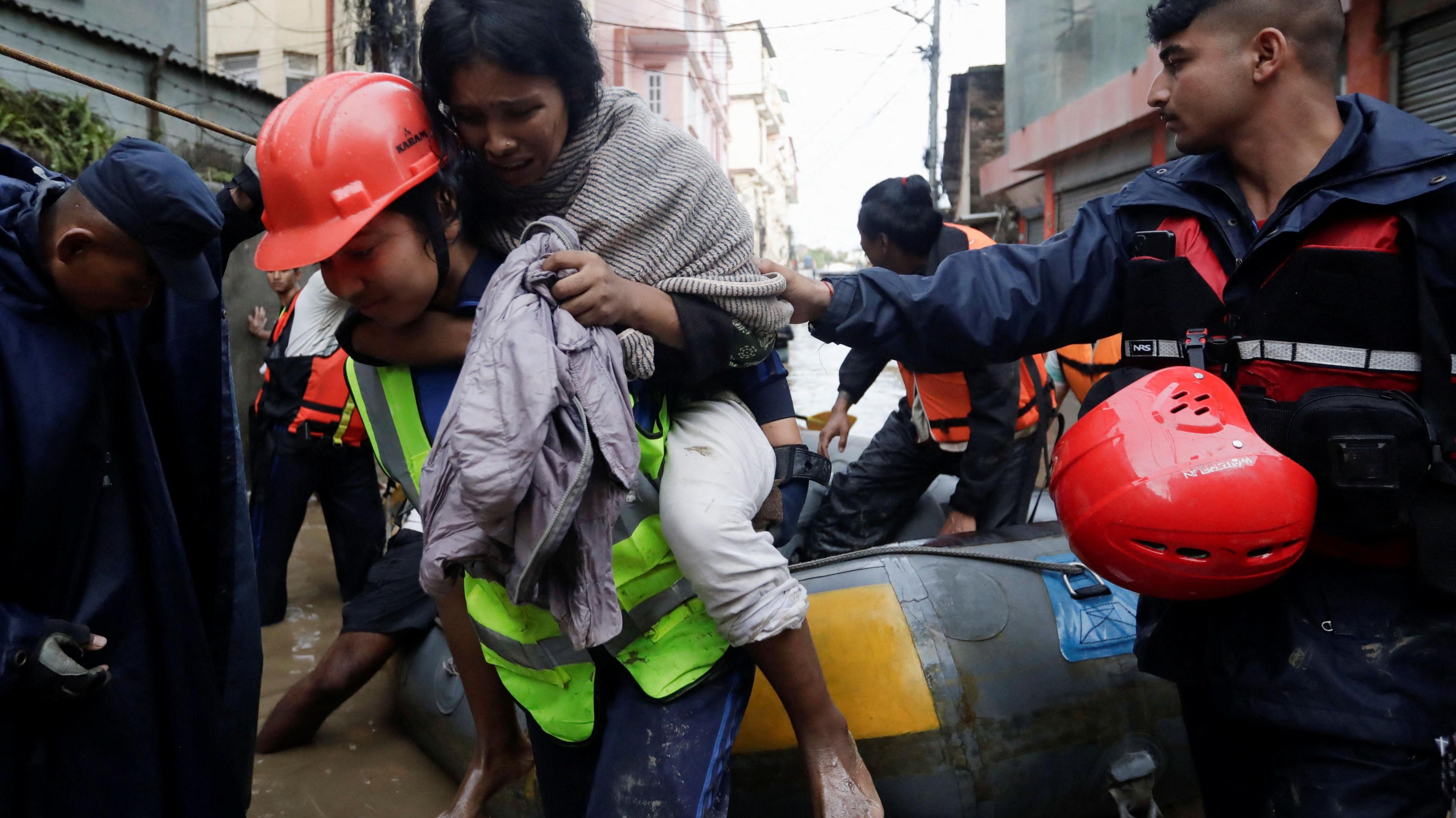 A police personal carries an injured woman from an inflatable raft after being rescued from a flooded area near the bank of the overflowing Bagmati River in Kathmandu, Nepal