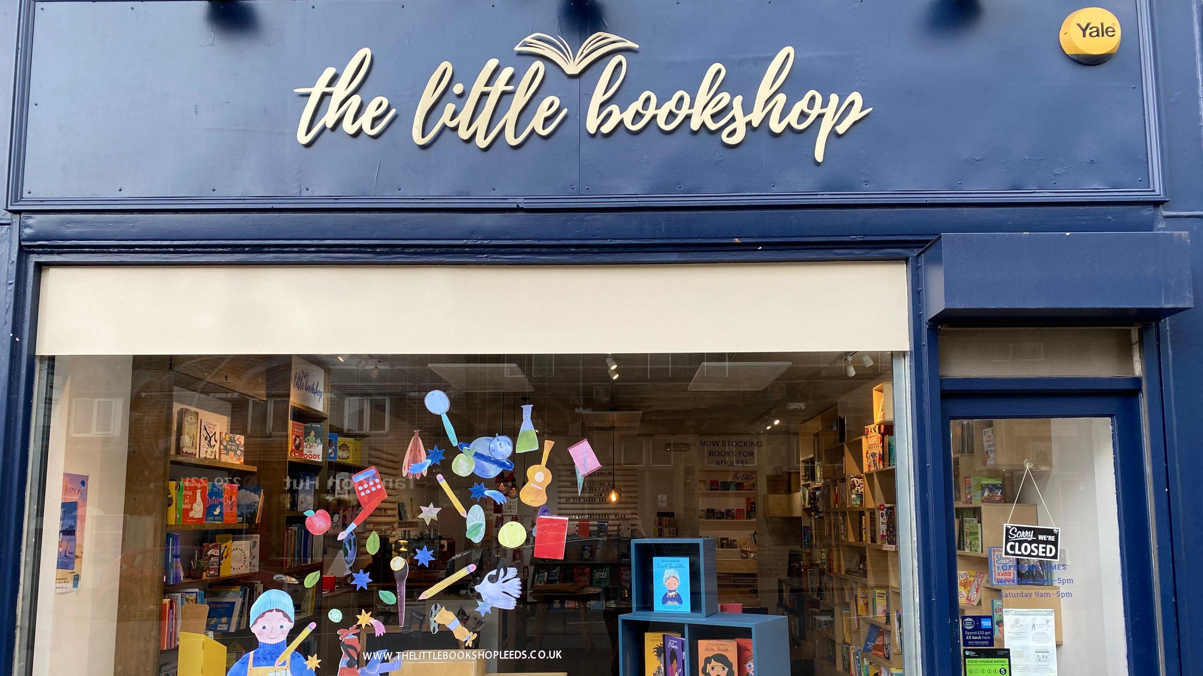 A shop front with dark blue exterior and a white sign reading: The Little Bookshop