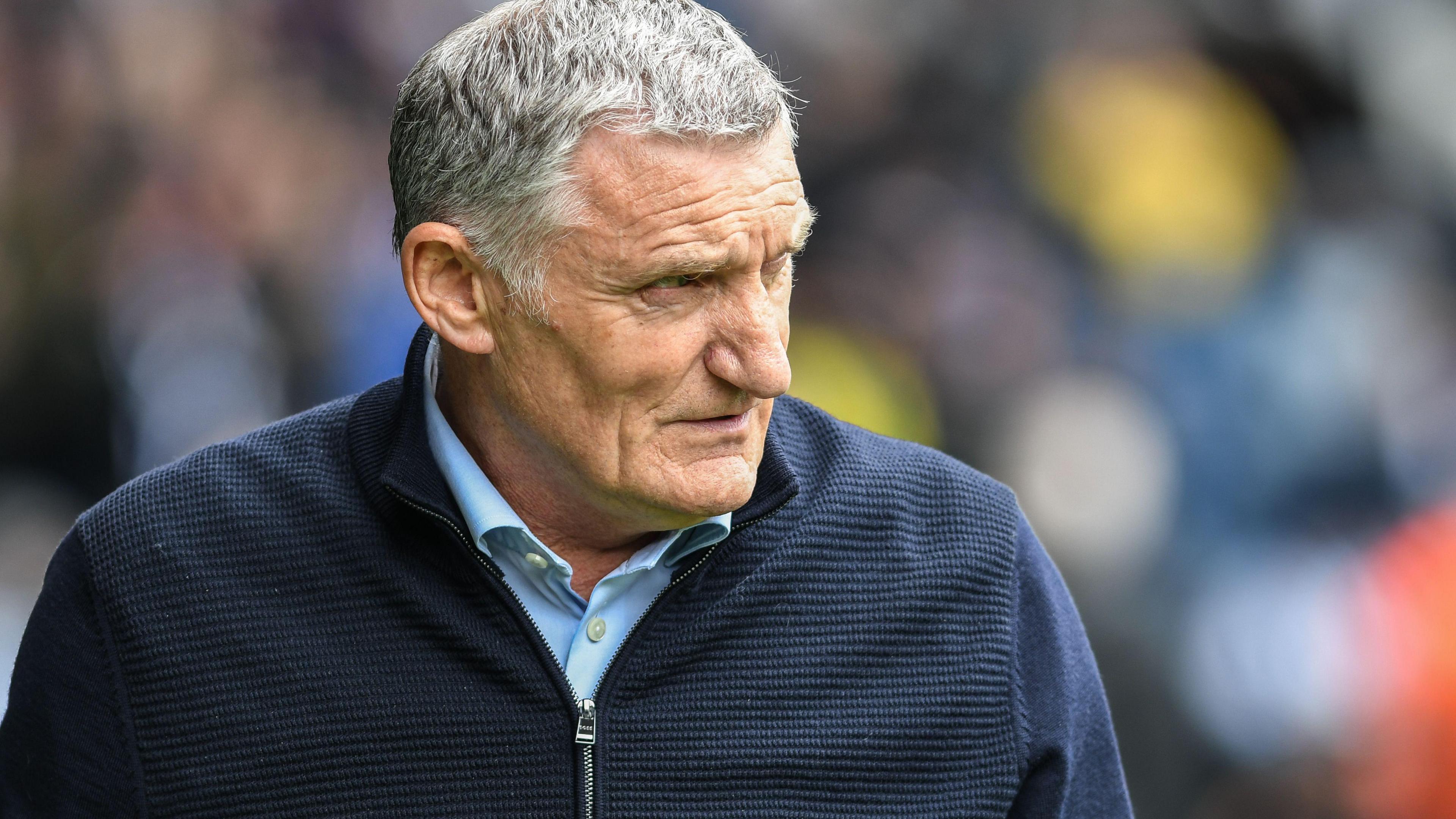 Tony Mowbray wearing a blue cardigan looks to his left