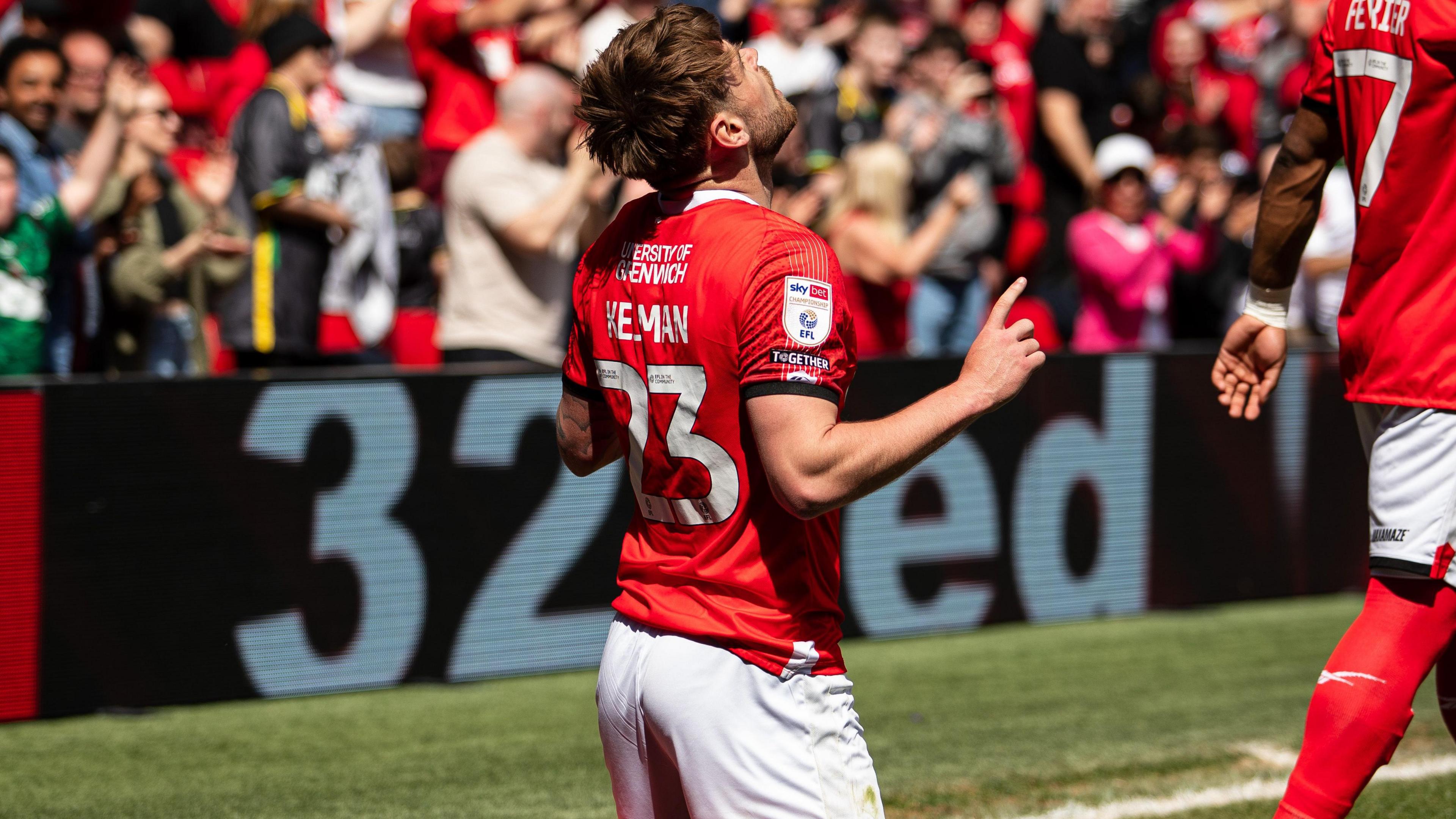 Charlie Kelman kneels down with both arms aloft, looking to the sky