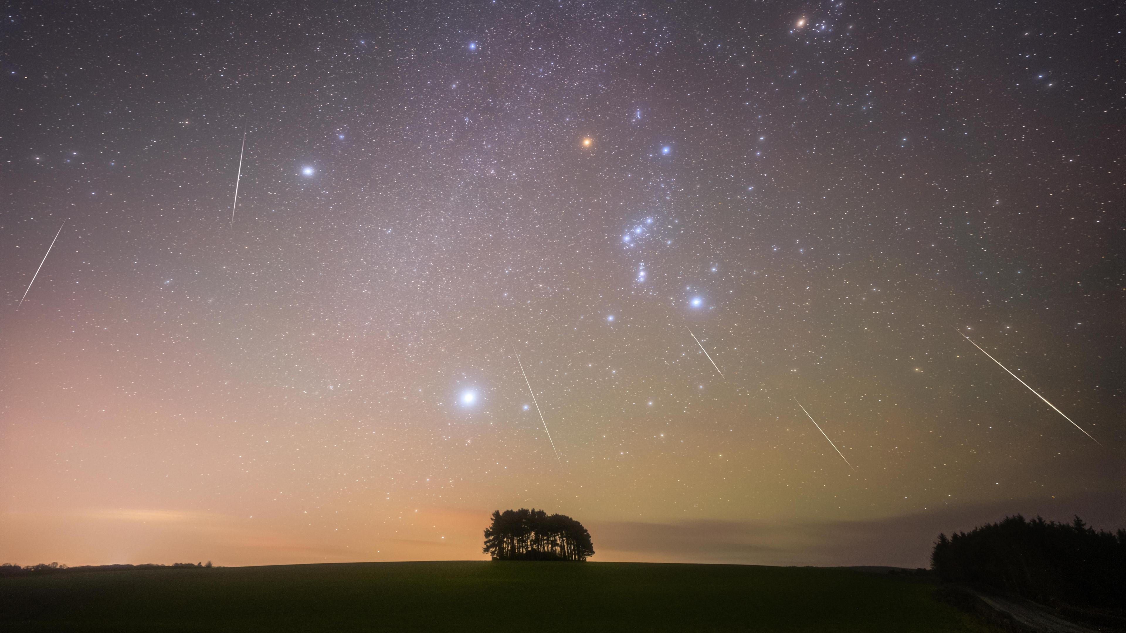 A night sky showing shooting stars blaze a trail above the countryside