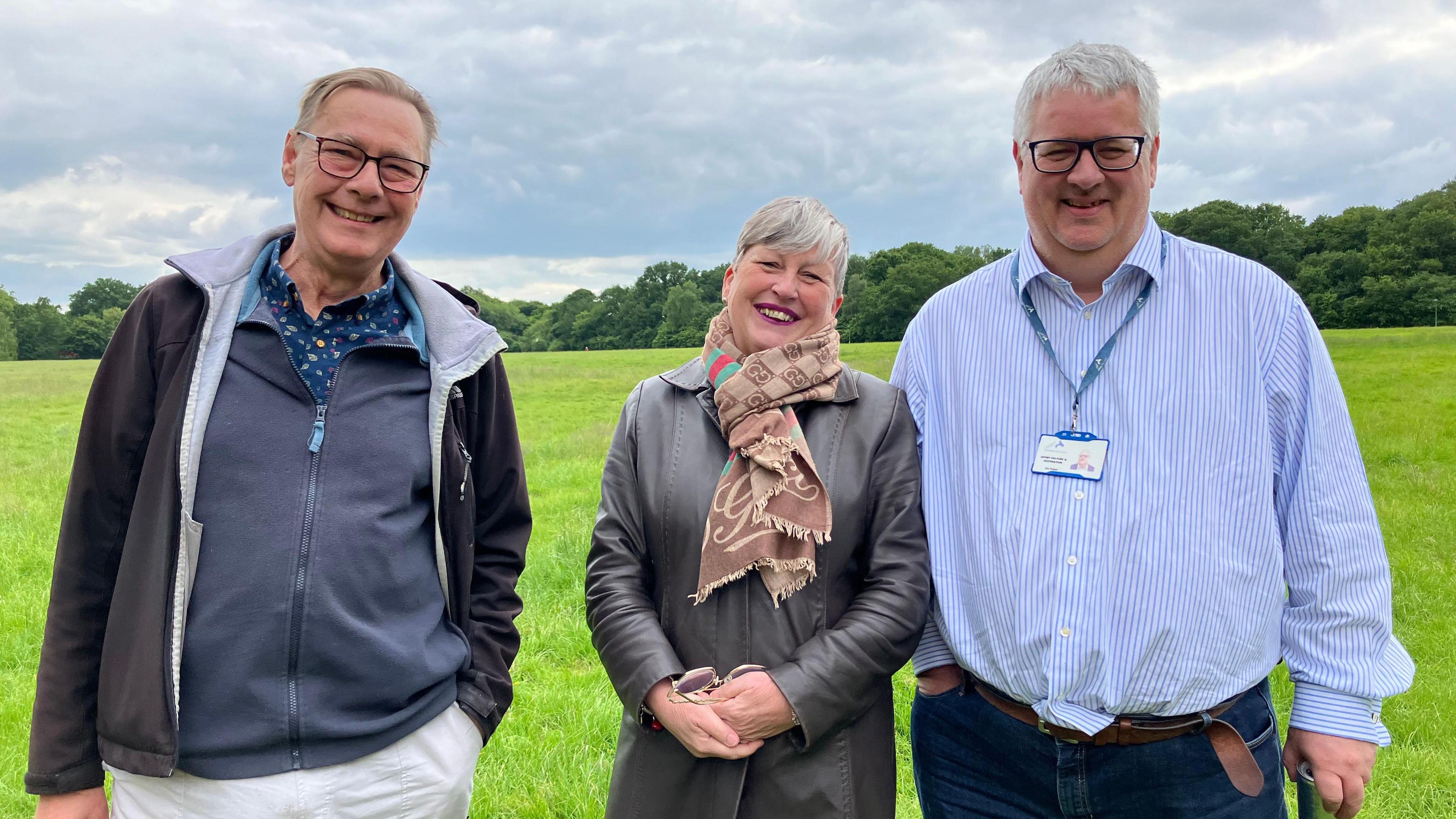 Mick Emerson, Lee House, Jon Hogan. All three are smiling at the camera - Mr Emerson is wearing glasse, a grey jacket over a blue underjacket which is over a spotted blue shirt and has short light hair. Ms House has a black coat on with a brown scarf while Mr Hogan has a blue pin-striped shirt on with jeans and a lanyard around his neck and his hair is short and white