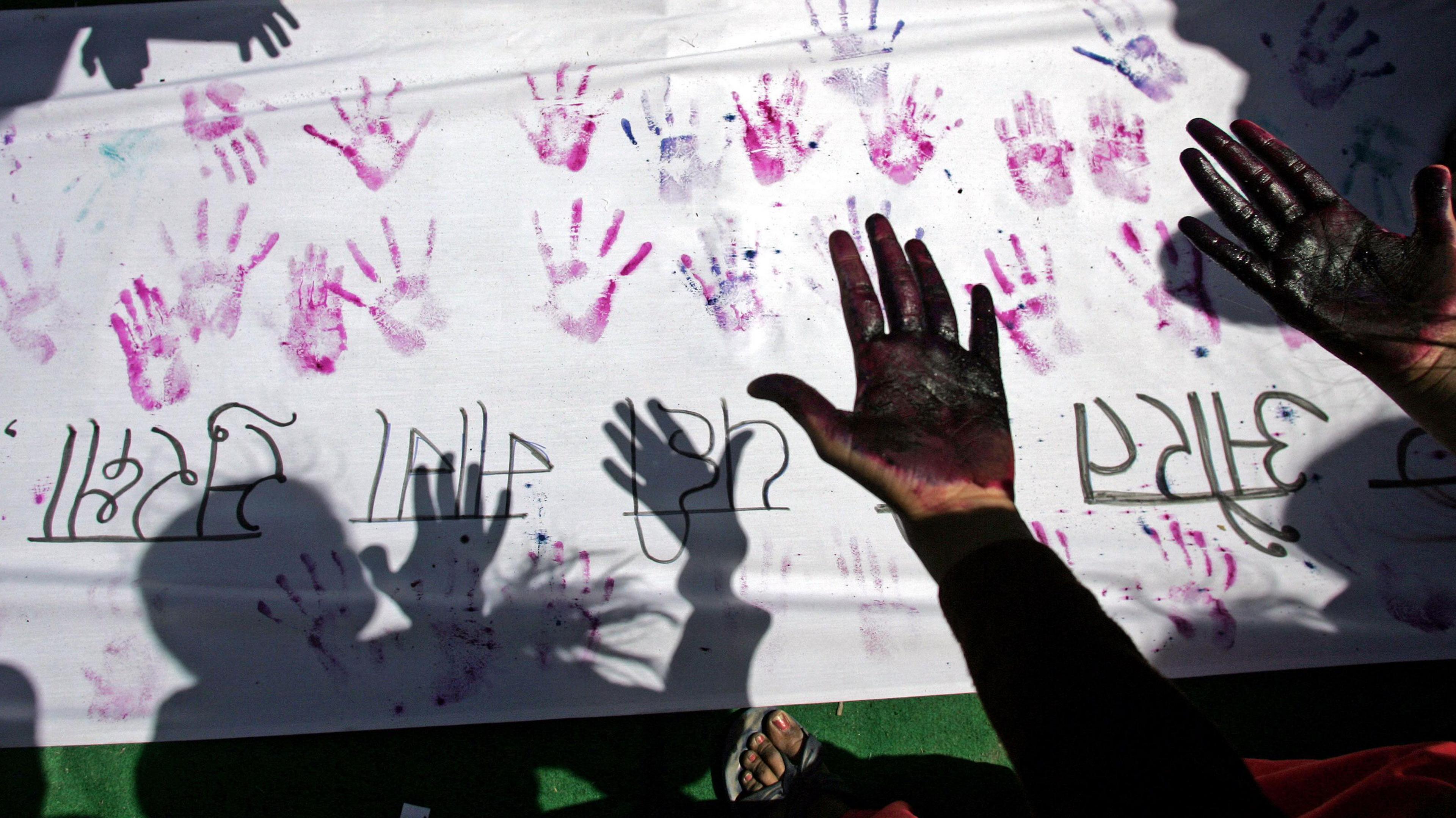 A file photo of An Indian woman looking at her hands after making a hand impression on a banner during a street march against sexual harassment and marital violence to mark International Women's Day in New Delhi