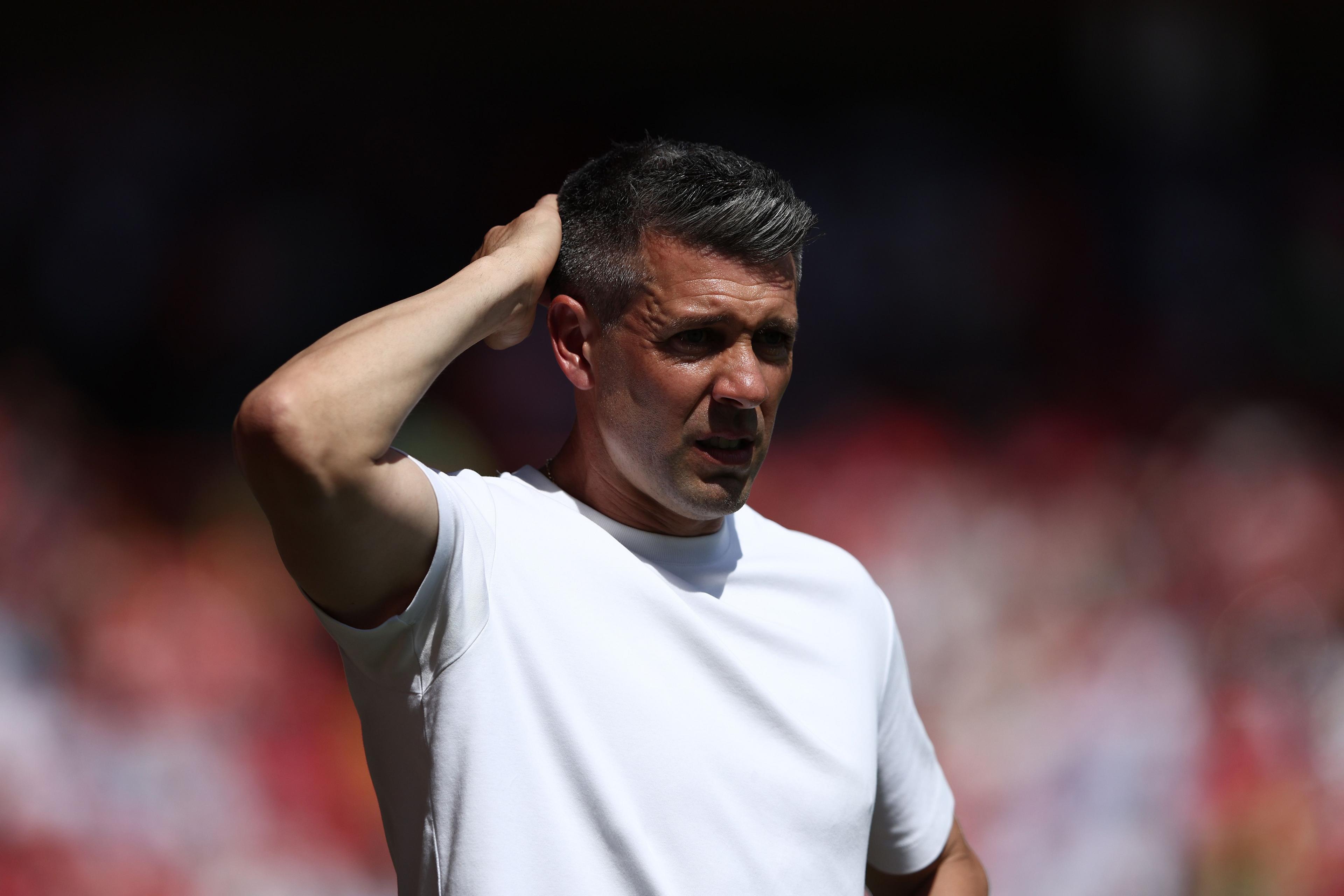 Paulo Pezzolano, wearing a white t-shirt, scratches the back of his head.