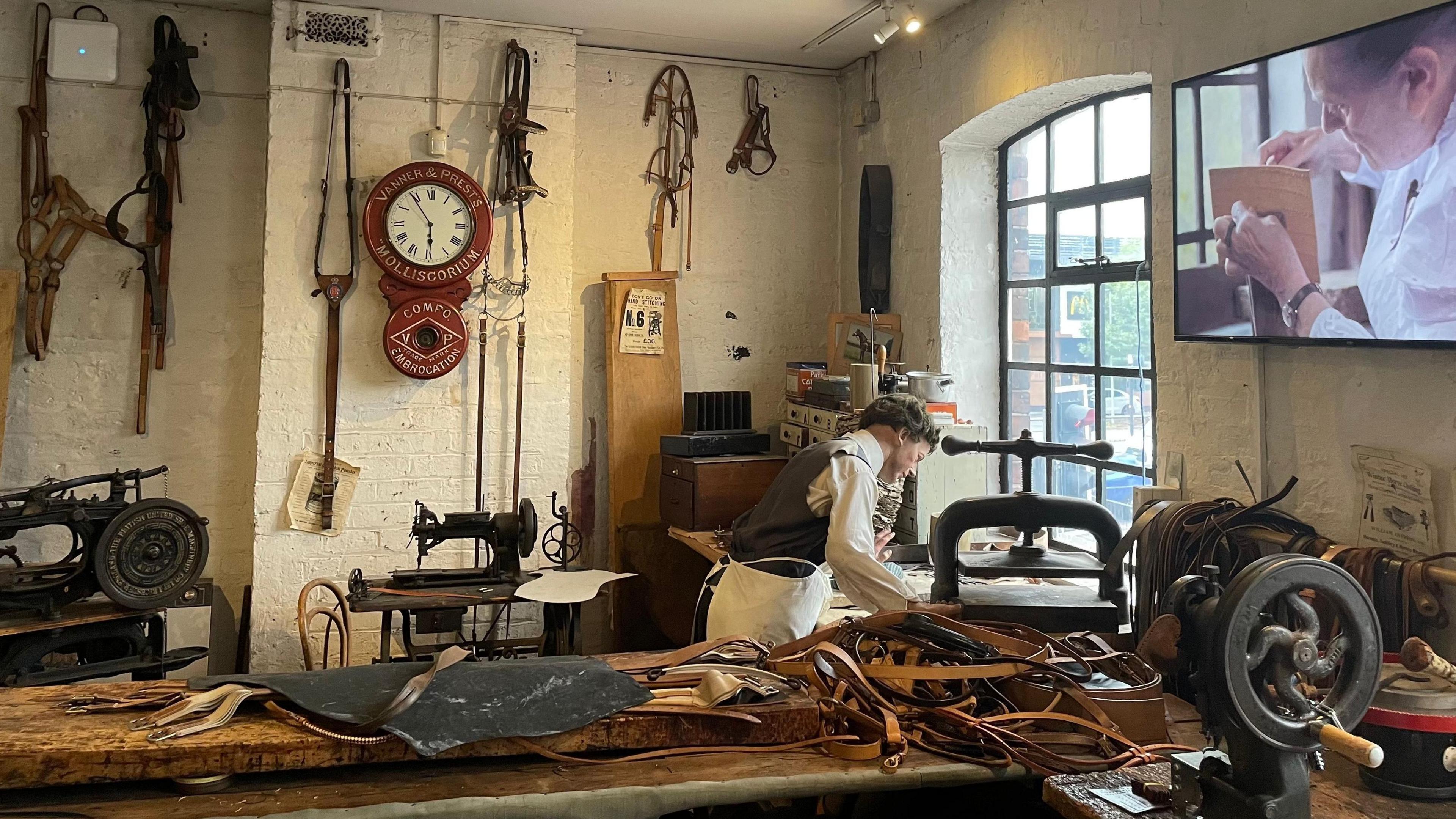 a leather museum displaying an old workshop, showing a man cutting leather on a machine
