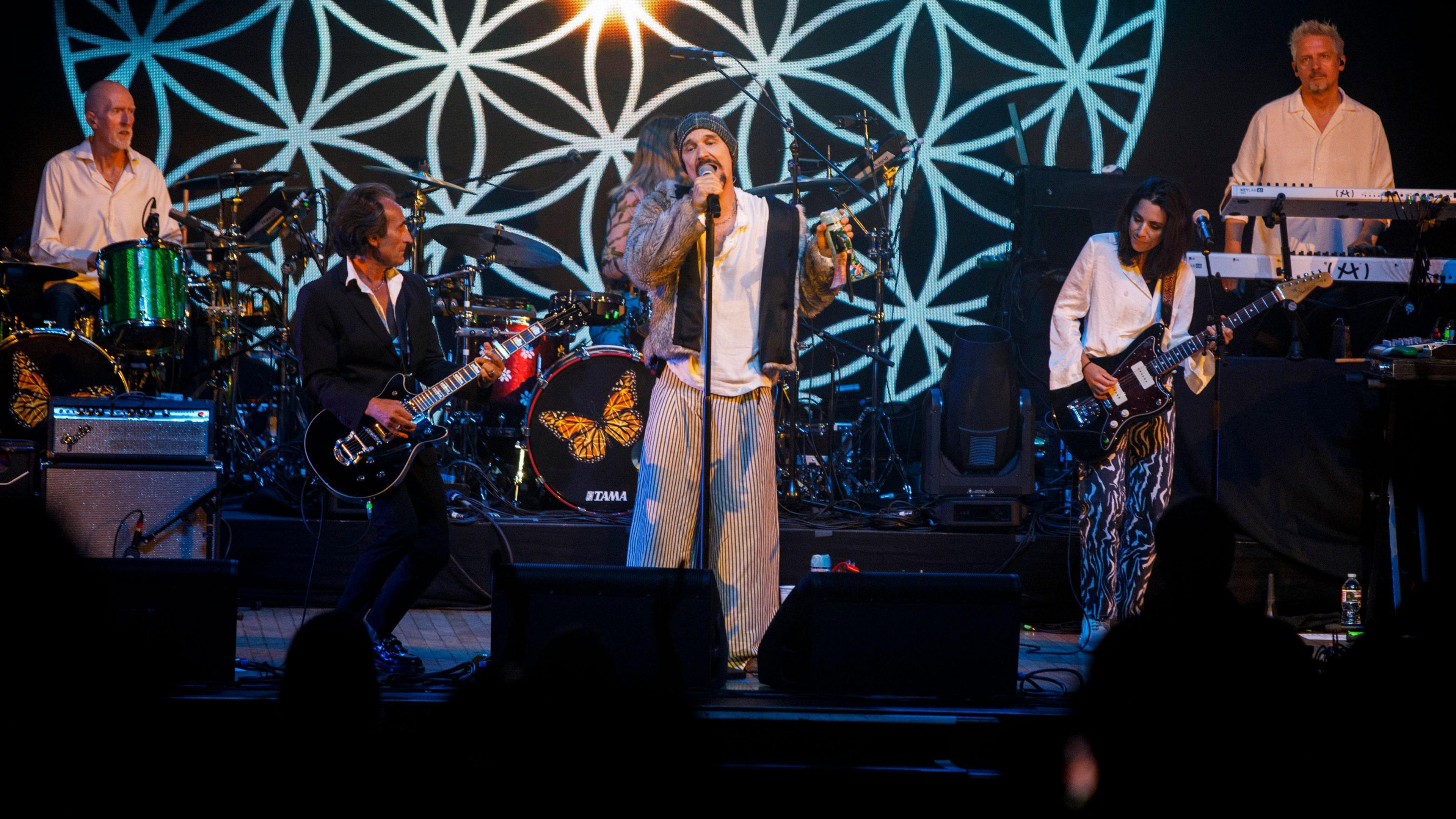 The band James performing onstage - band members are pictured playing guitars, on drums and on keyboards