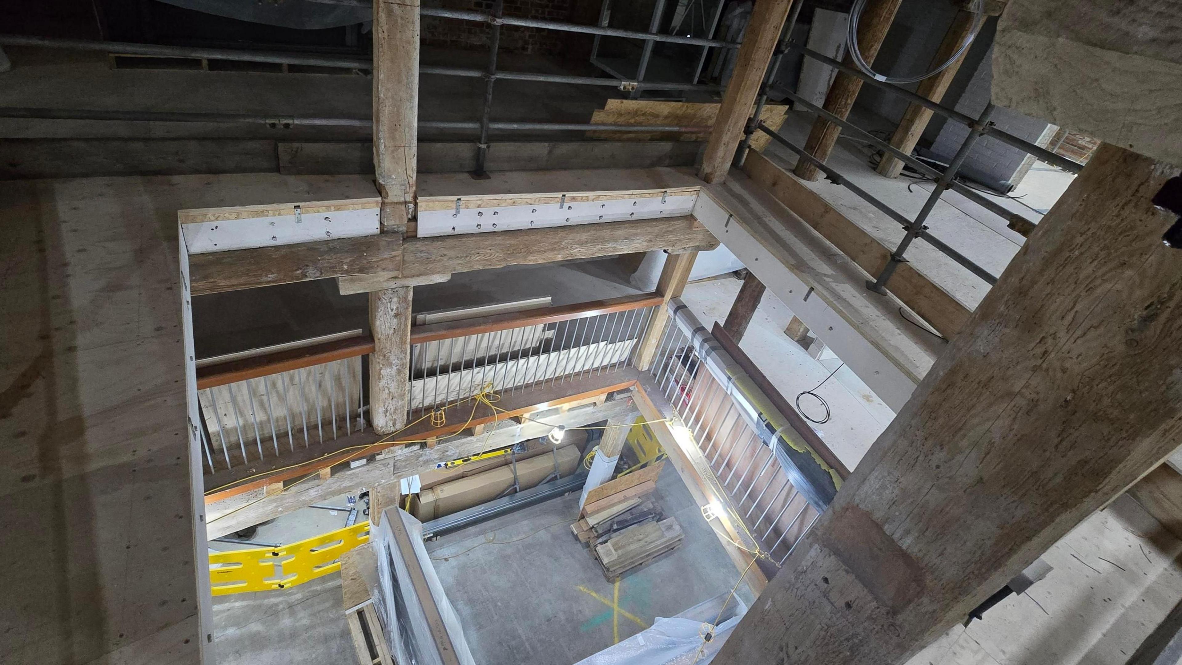 A view of Poole Museum with redevelopment work going on - the building has thick oak beams and the three floors are empty with building materials and cables scattered around.