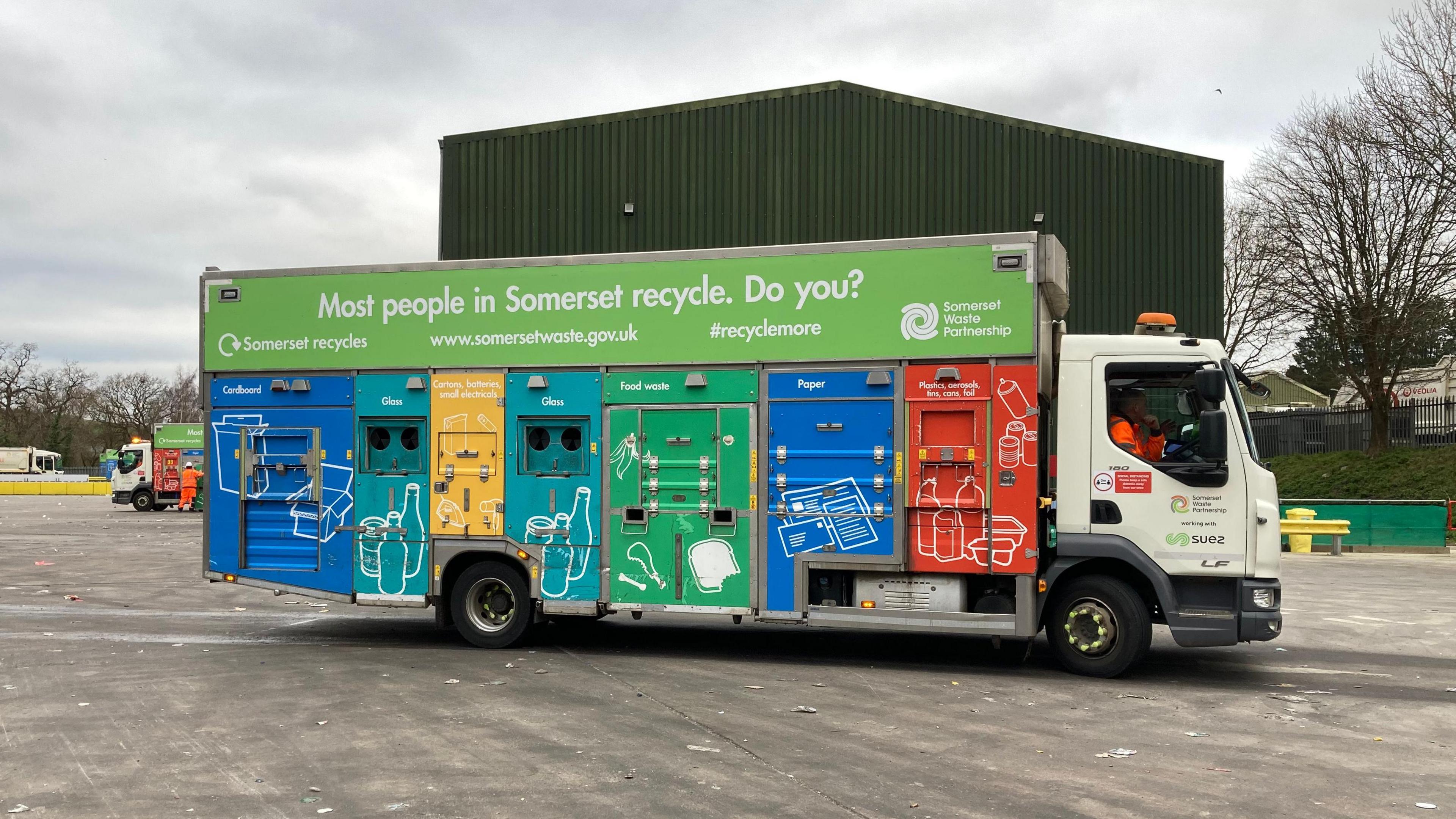 A recycling lorry in a depot with the words: "Most people in Somerset Recycle. Do you?" written on the side of it.