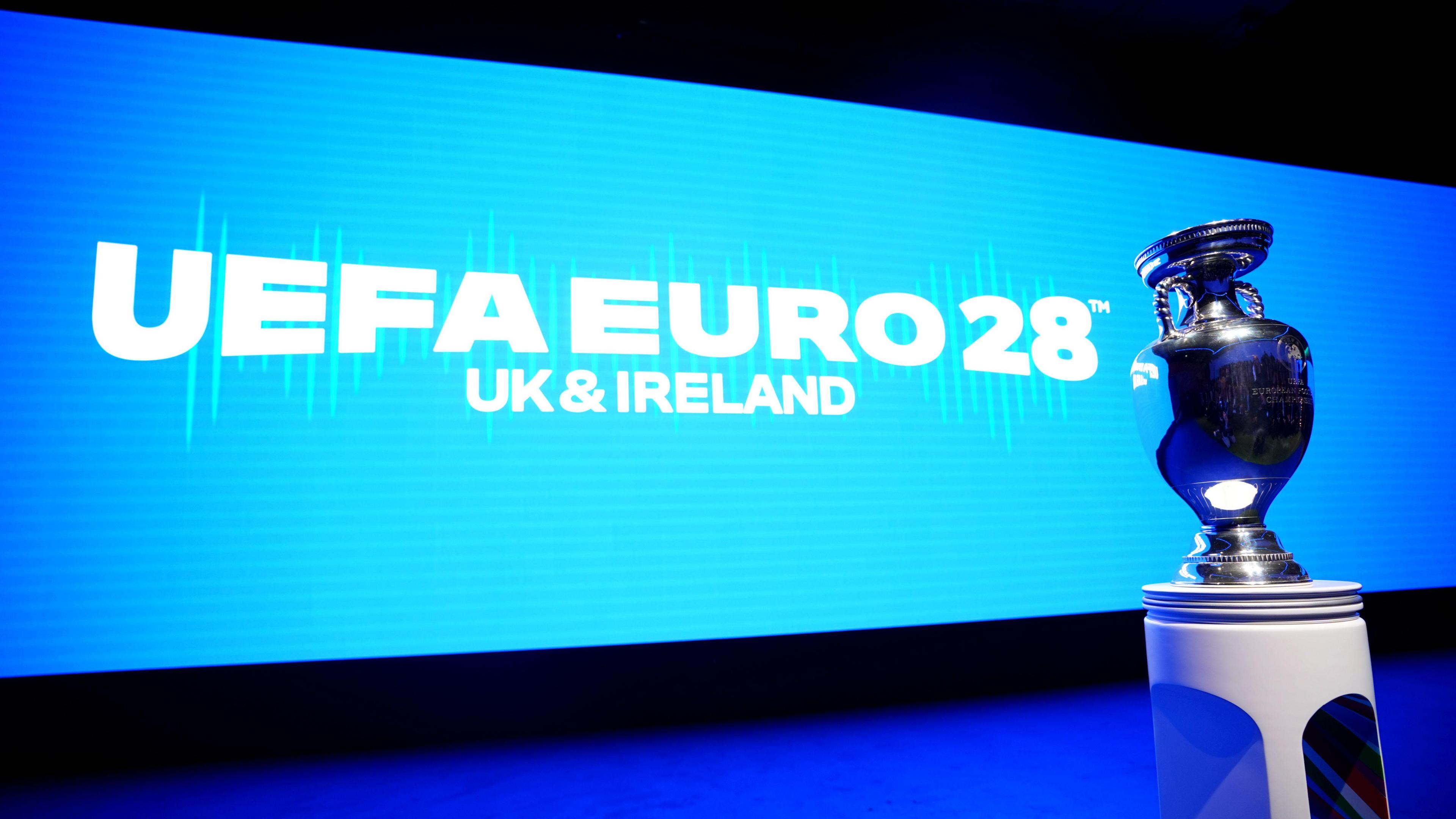 A wide screen with text reading UEFA Euro 2028: UK and Ireland, with a trophy next to it