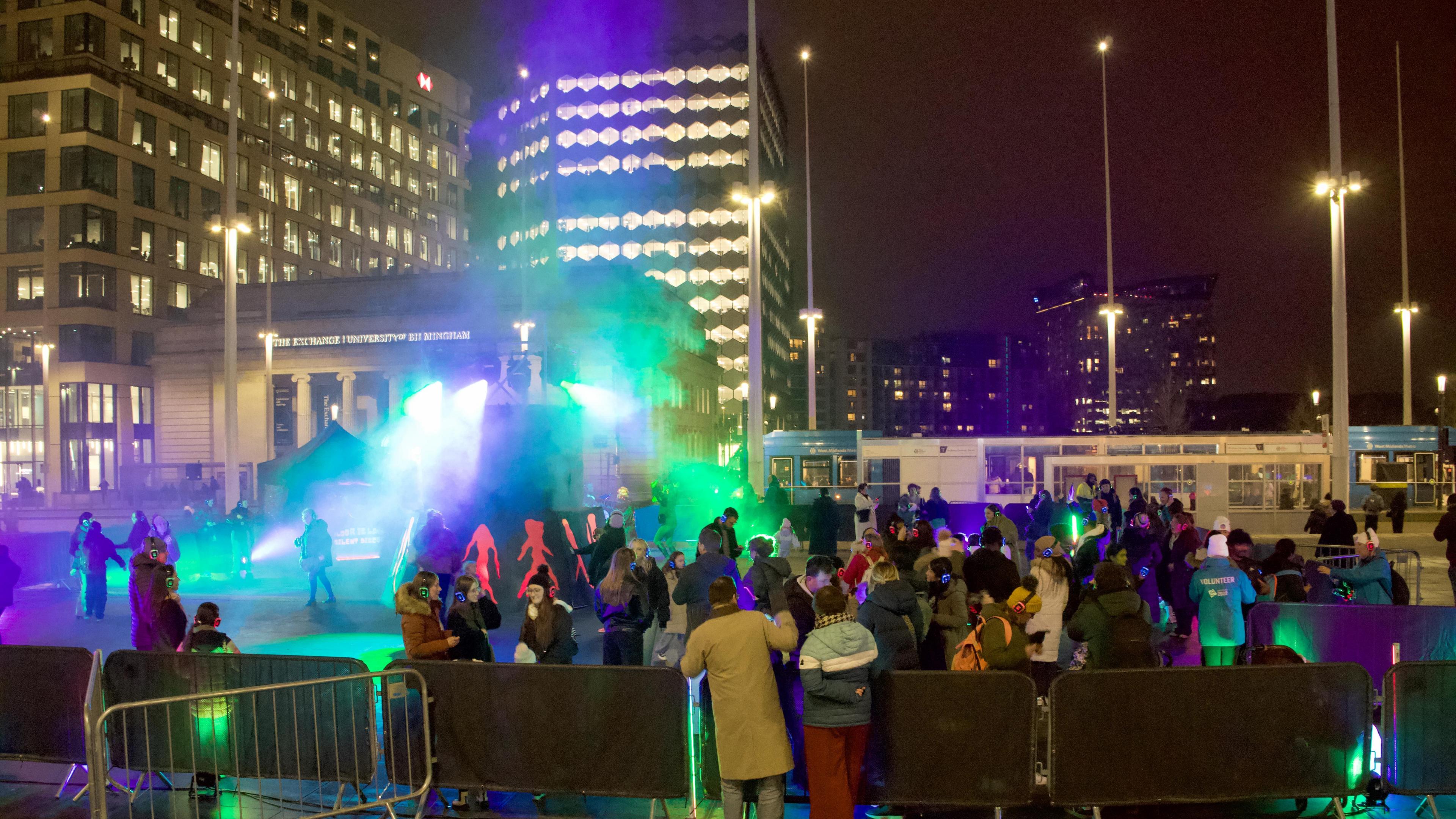 People wearing headphones at an open air silent disco with green lights