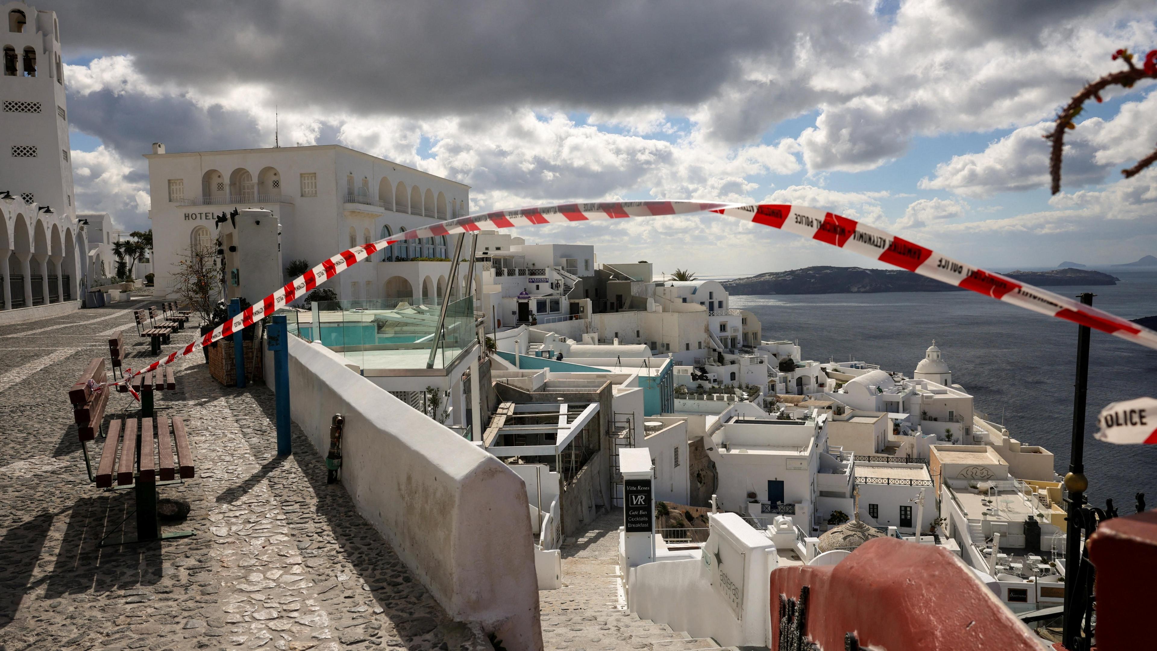 Police tape tied to bench at entrance to steps in village of Fira, Santorini, leading down to lower seaside part of village