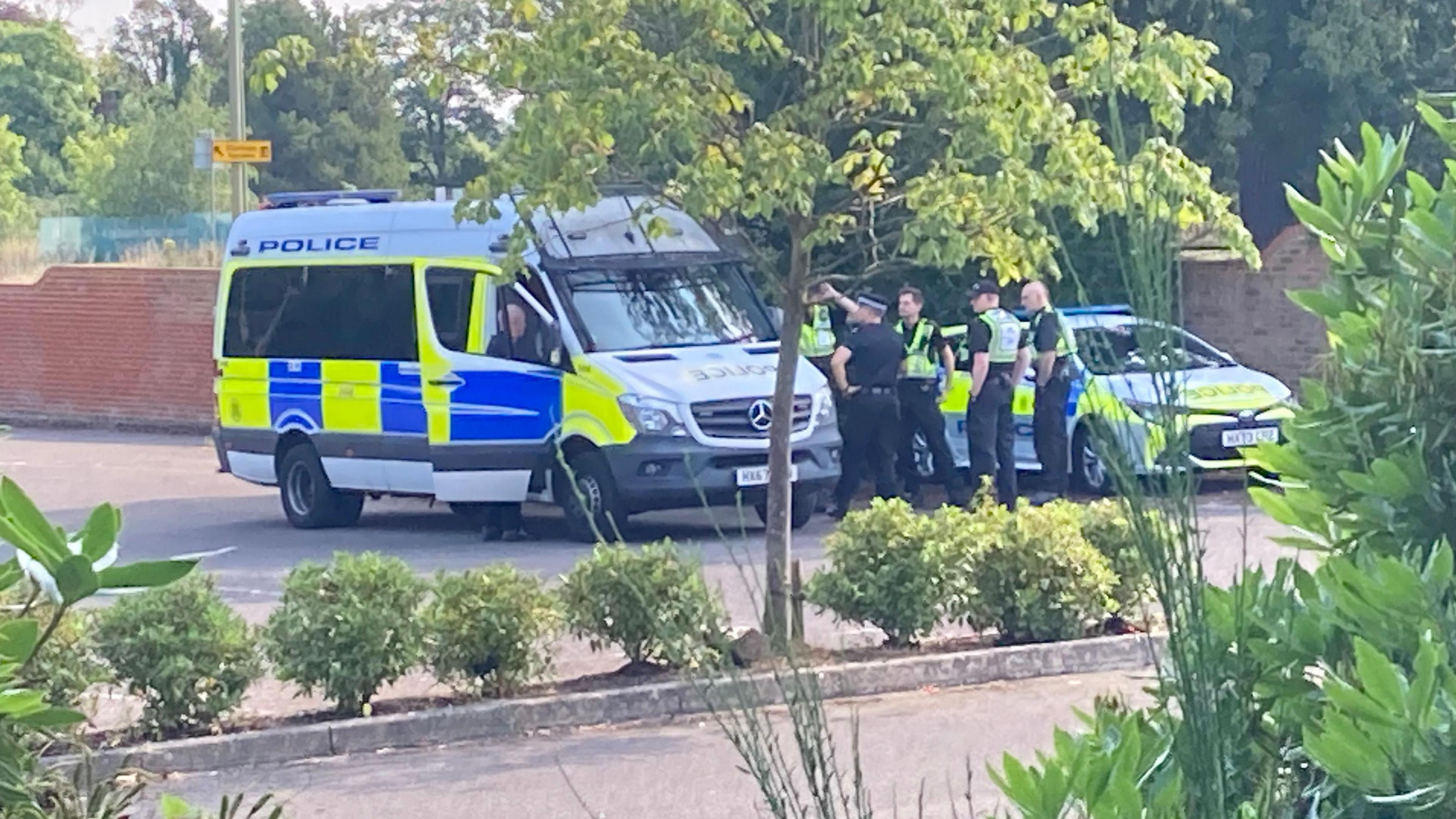 Police van and car park with some officers standing by