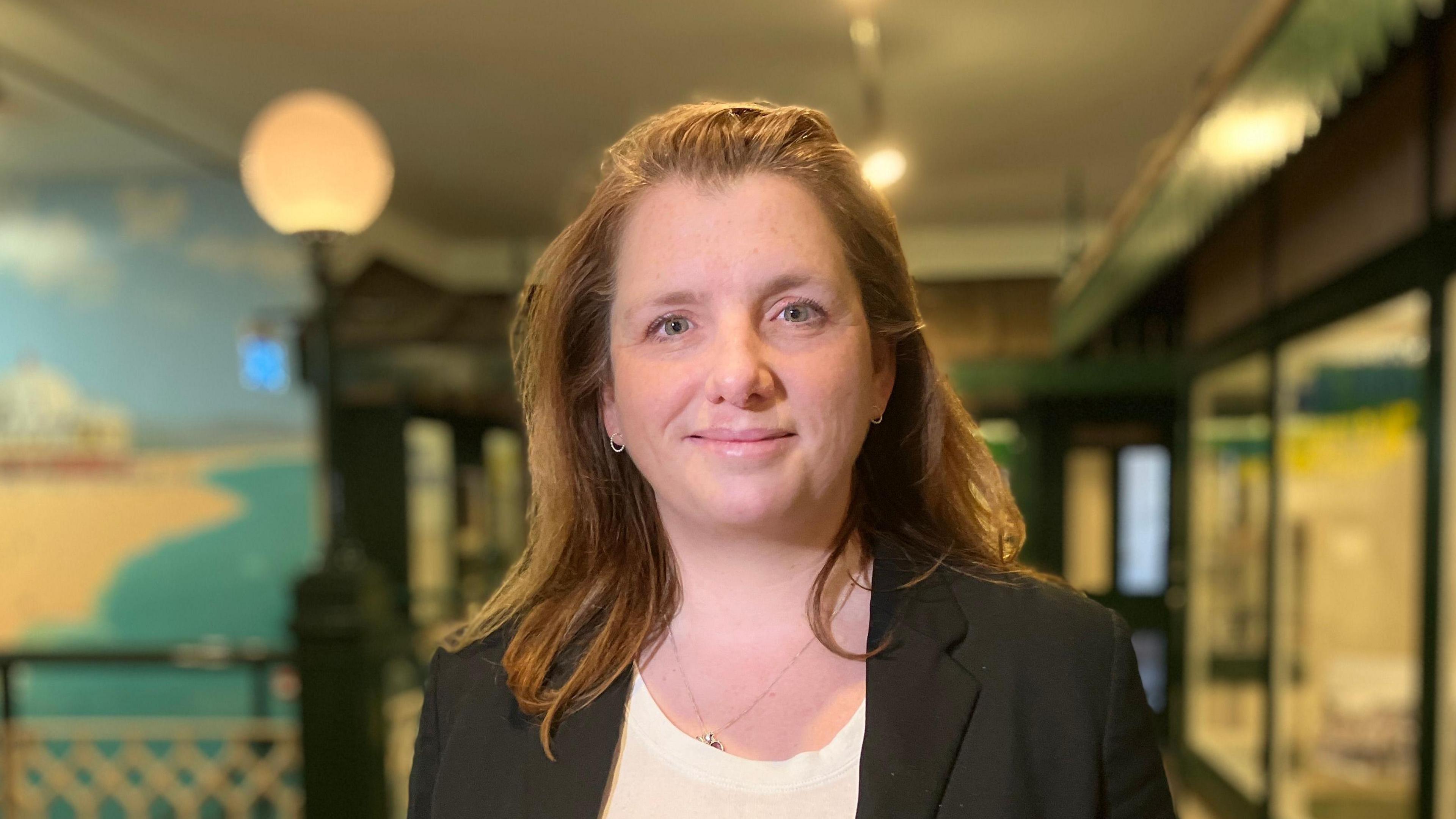 A head and shoulders image of MP Alison McGovern. She is wearing a black blazer over a white top. She is smiling and looking into the camera.