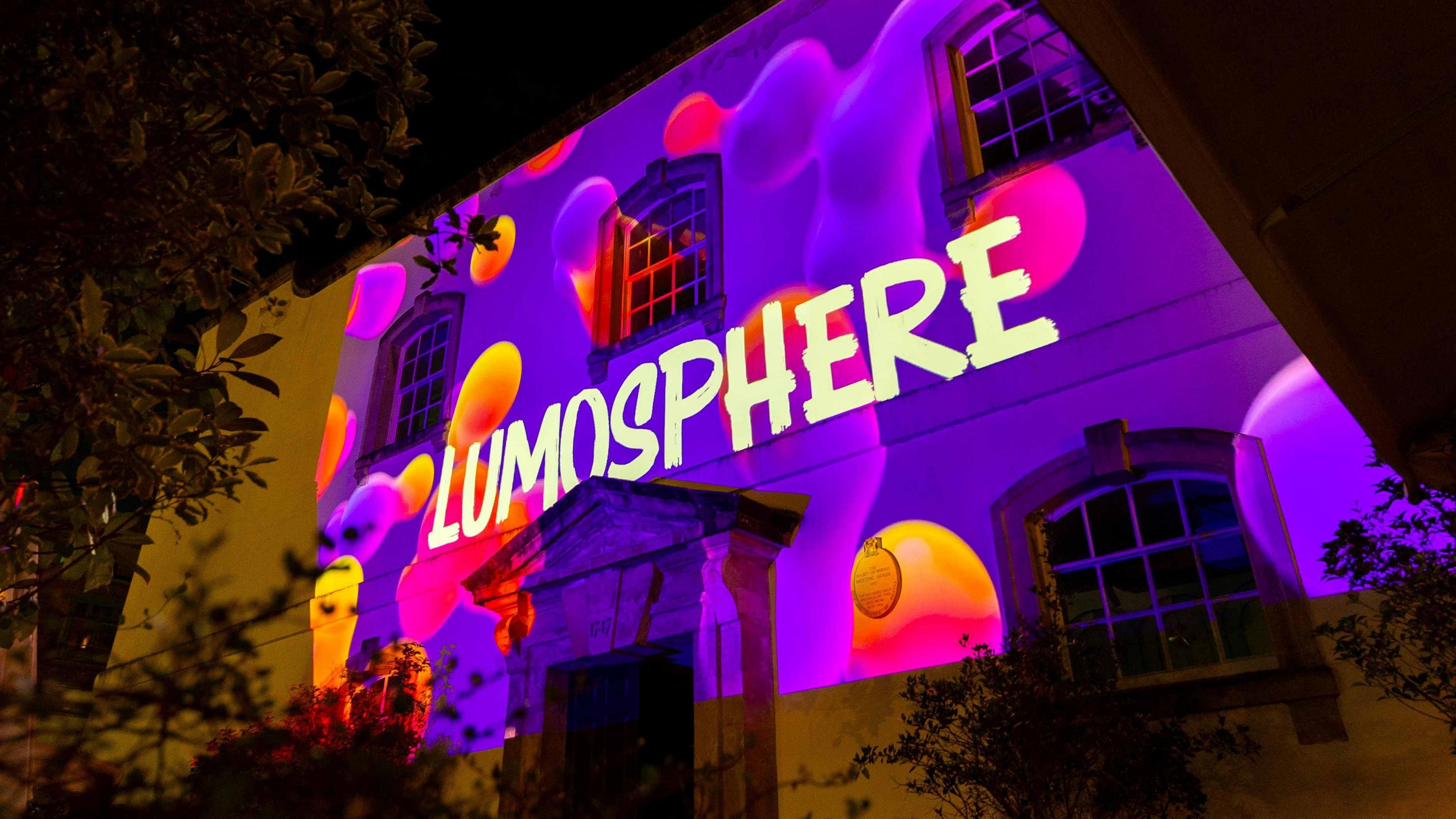 A building with a purple and orange projection. The Lumosphere logo is also featured