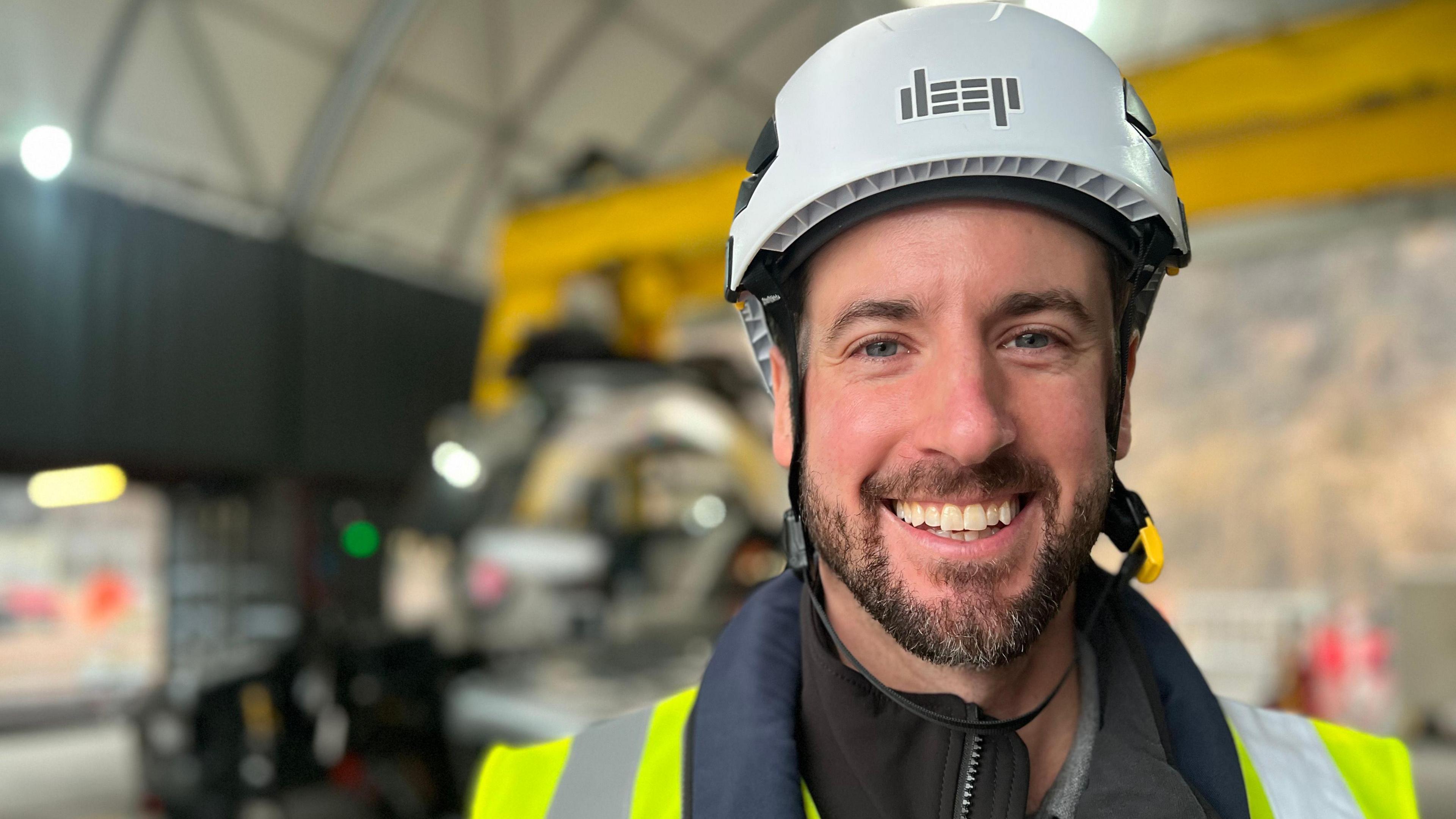 Sean Wolpert, Deep President in a hardhat with a futuristic submarine behind him