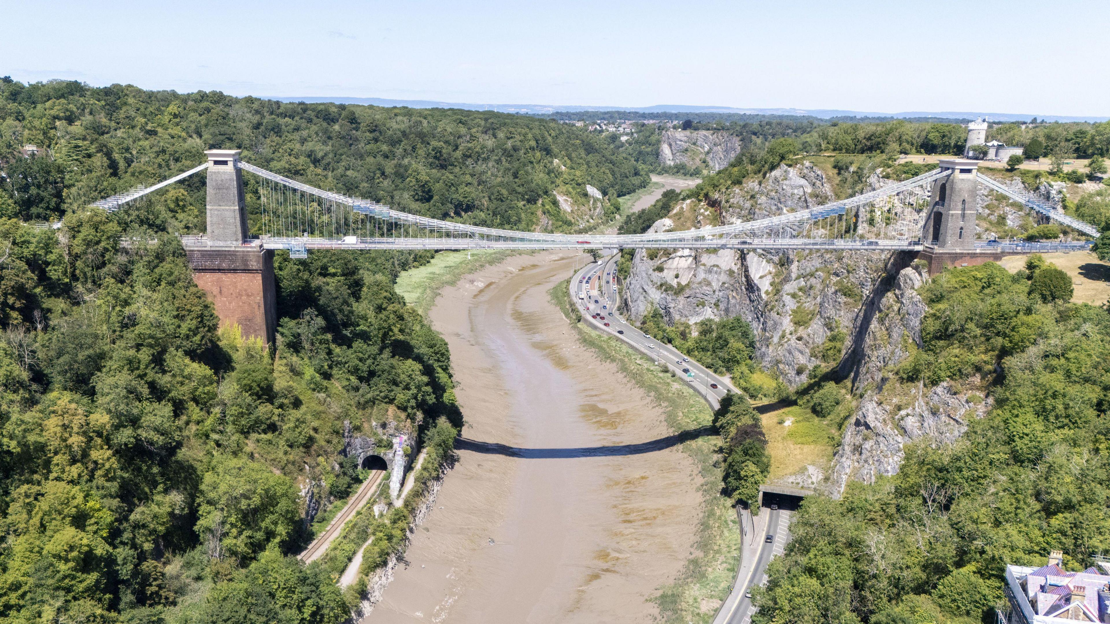 The Clifton Suspension Bridge in Bristol, a historic and iconic Victorian bridge that goes over the Avon Gorge in Bristol. The photo has been taken on a sunny day and cars are driving on the road beneath.