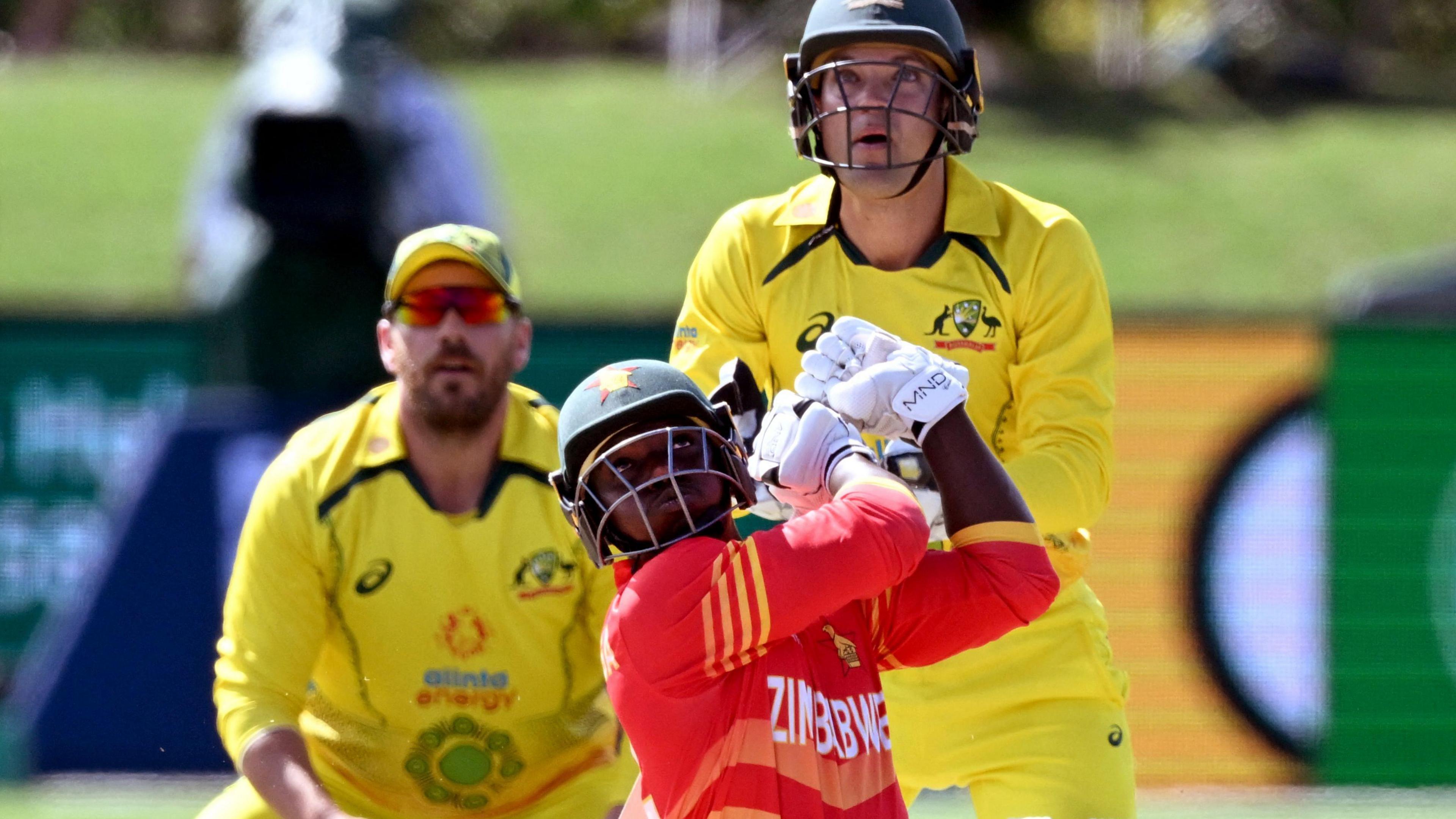 Zimbabwe batter Tony Munyonga hits out, watched by Australia wicketkeeper Alex Carey, during an ODI in 2022