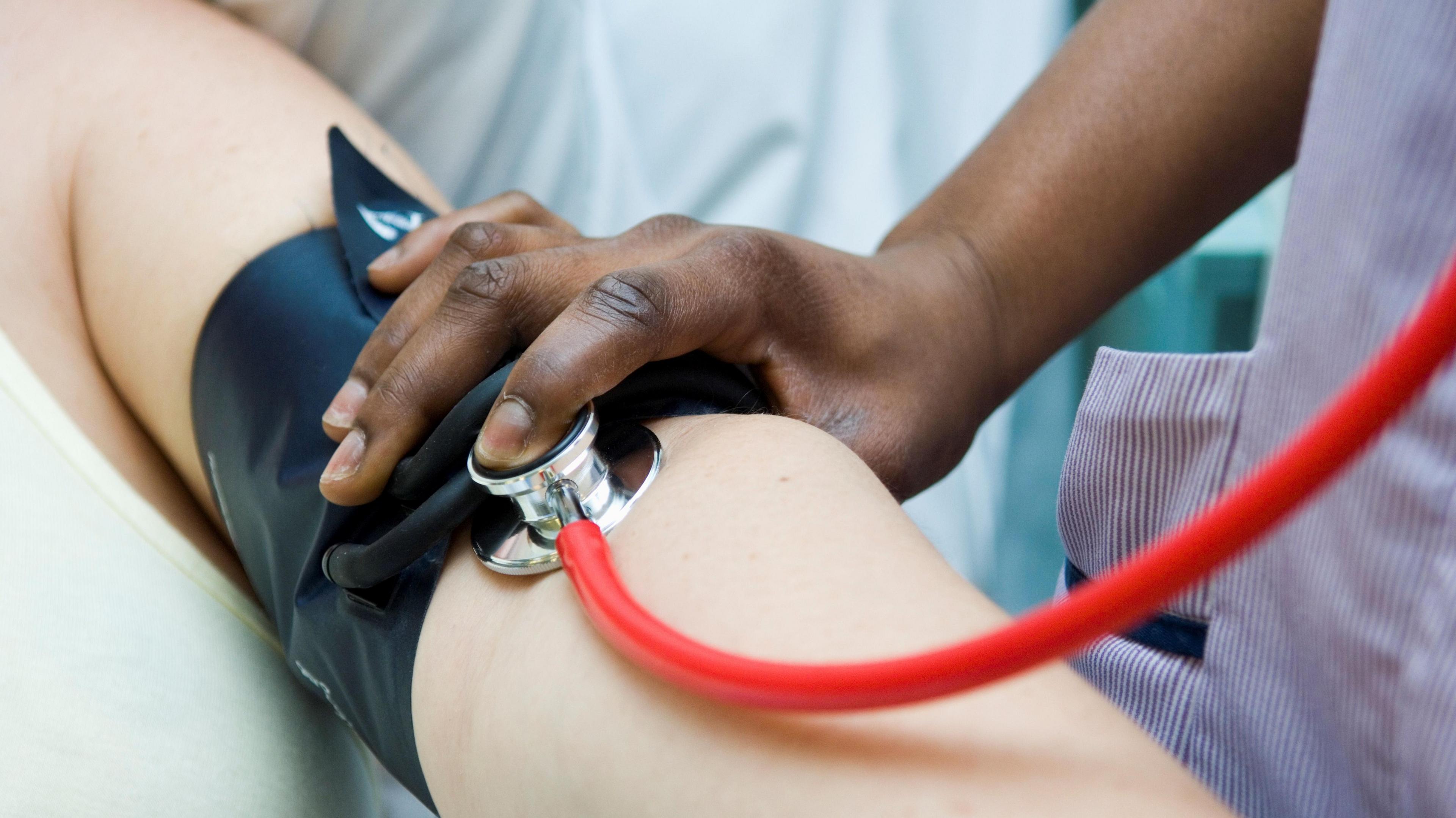 Checking pulse in hospital. An arm is outstretched as a nurse checks the patients blood pressure. 