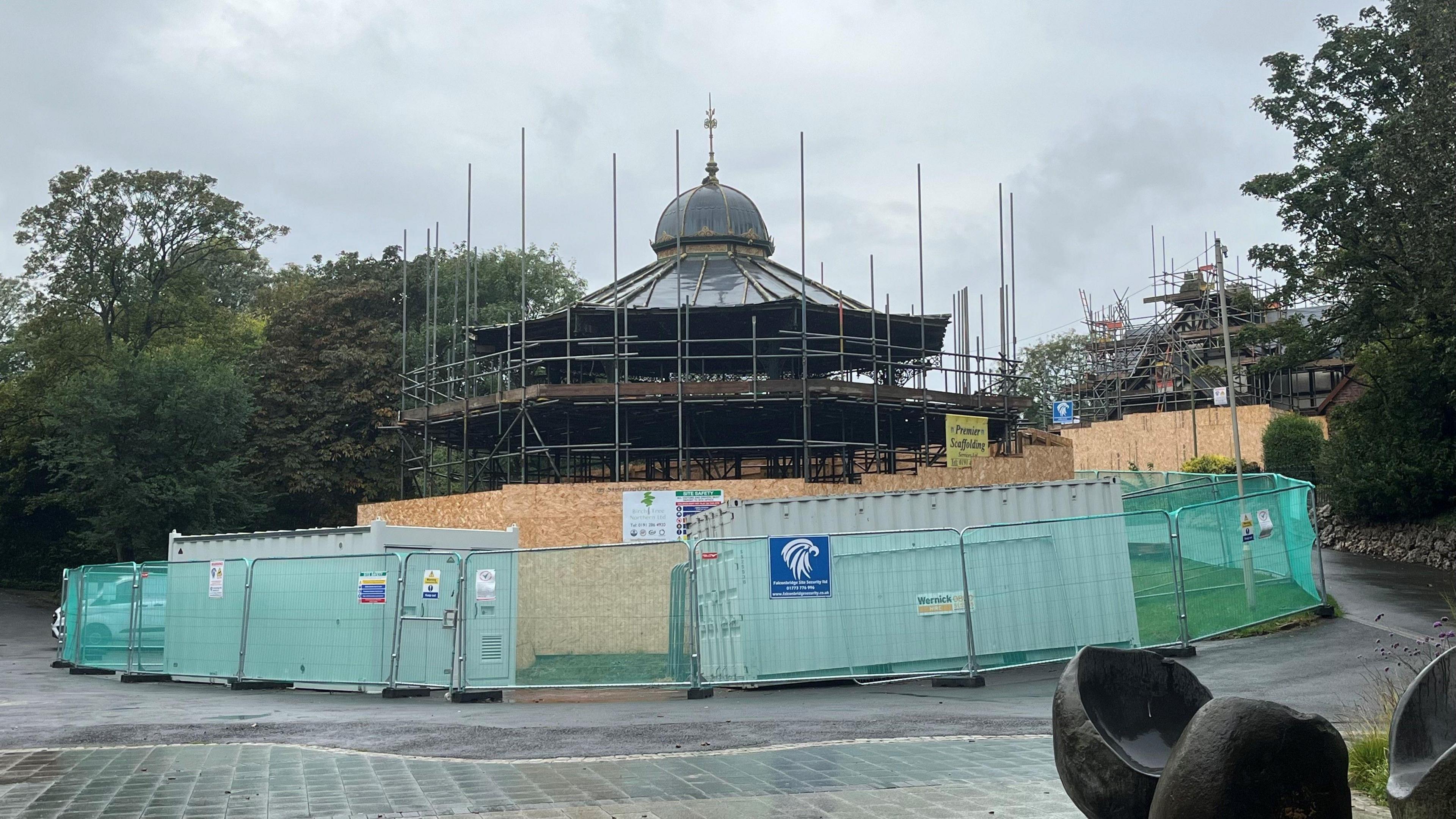 Roker Bandstand is covered in scaffolding and surrounded by wooden and metal fencing. It has an ornamental dome-like roof.