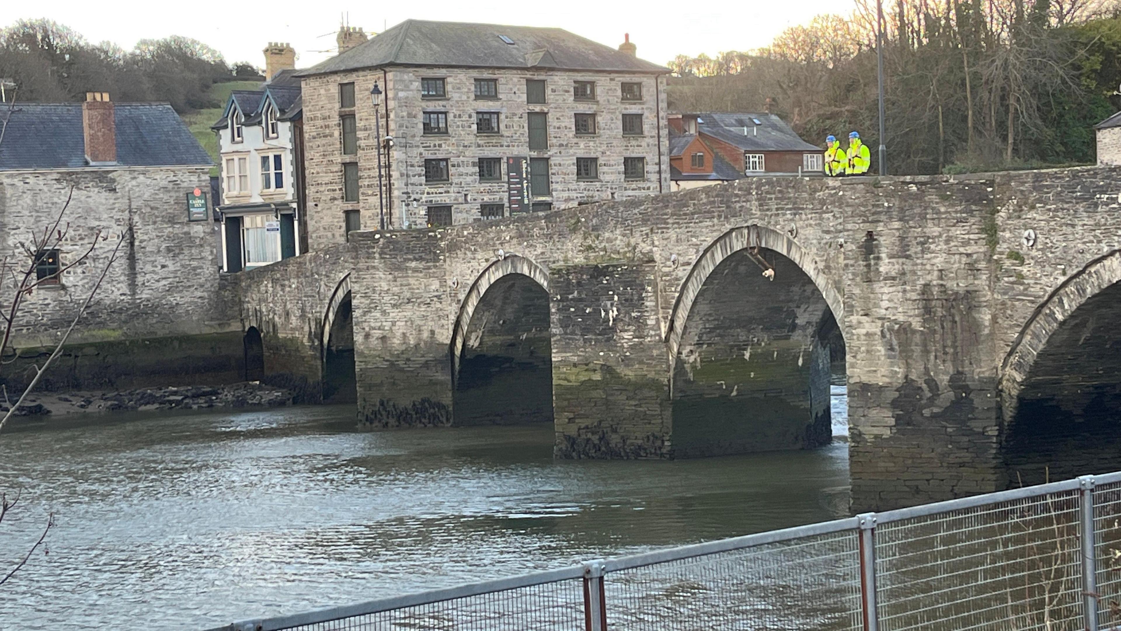 Dau berson mewn siacedi llachar yn sefyll ar bont dros Afon Teifi yn Aberteifi ble mae ofnau bod dyn wedi mynd i'r afon