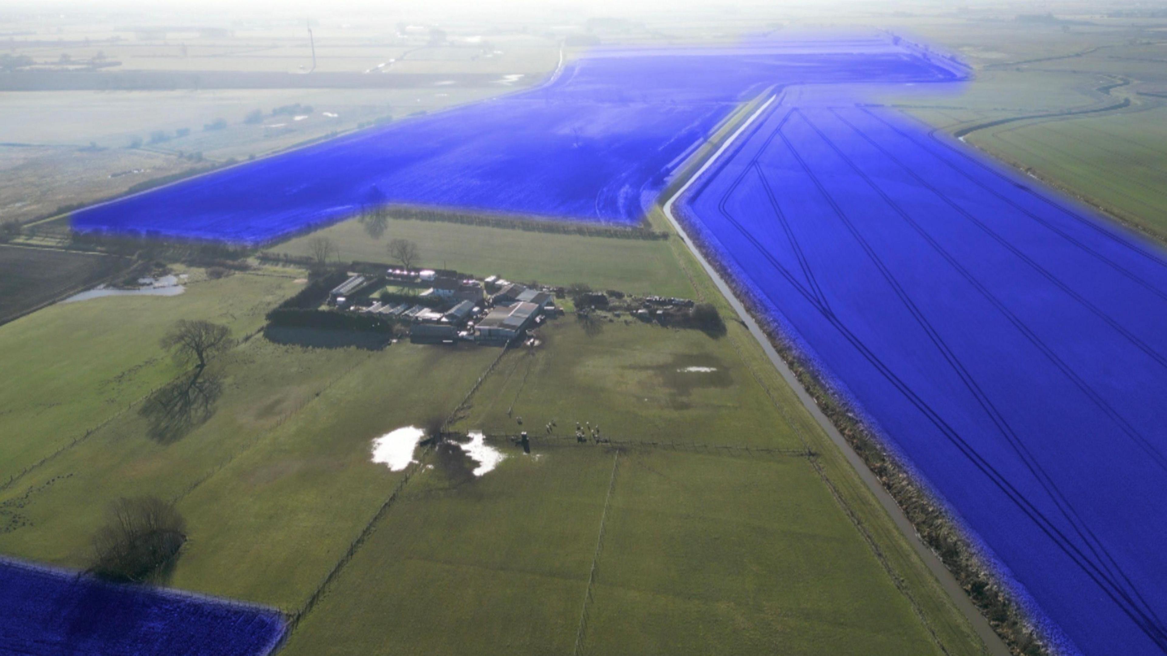 An aerial shot of a small farm holding in the middle of large fields. To the sides are fields that are shaded over in blue to act as an indicator for where a large solar farm will be.