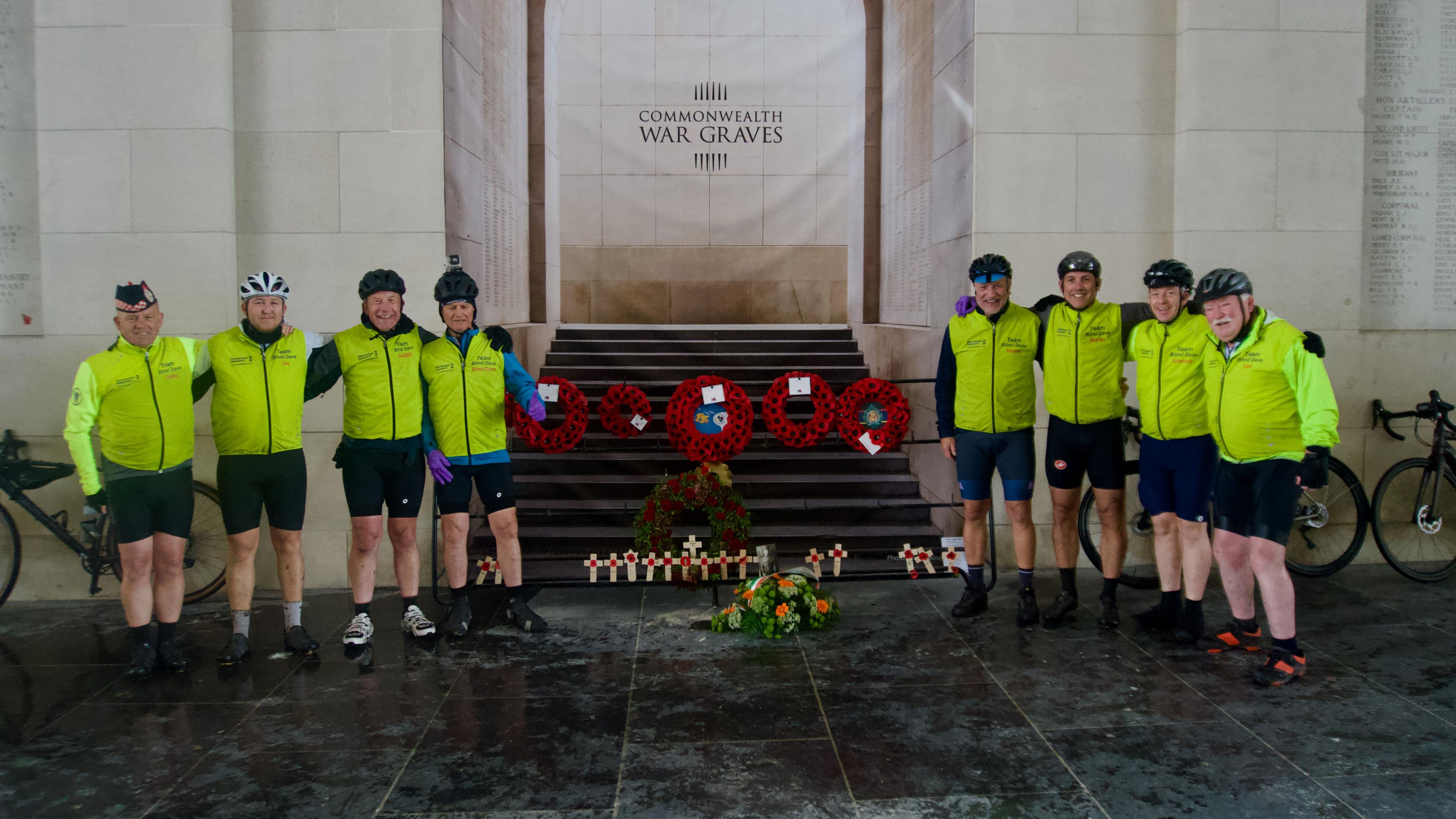 Eight cyclists with wreathes at the Menin Gate memorial in Belgium