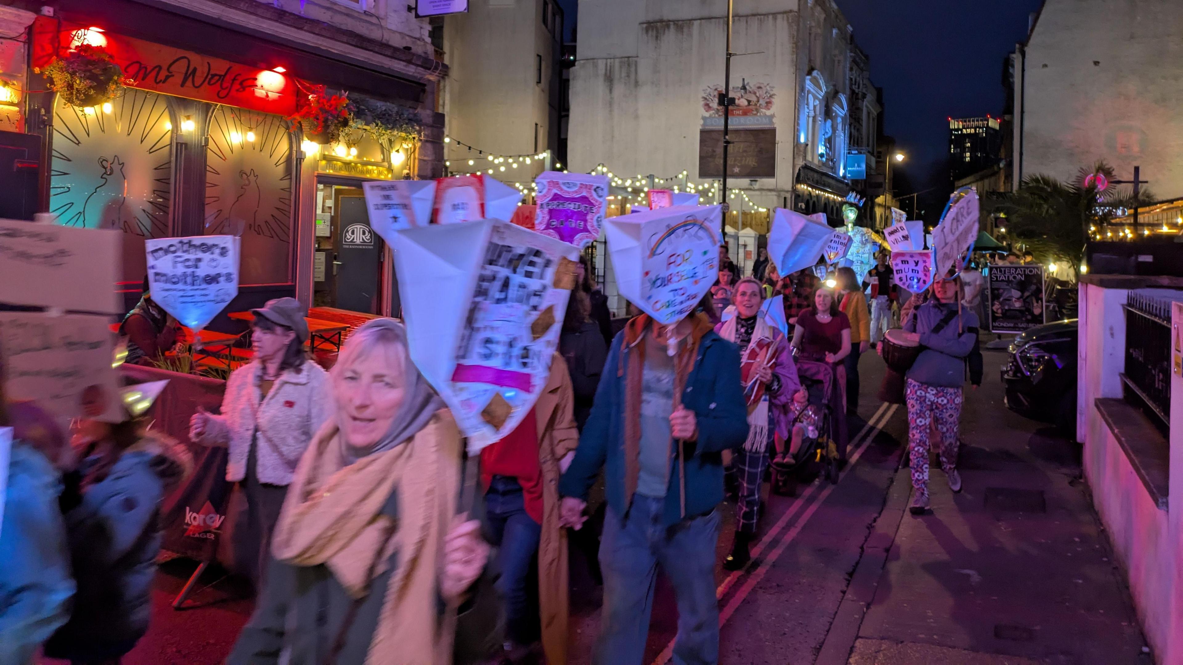 A line of women march through Bristol at night bearing placards as part of an event to highlight issues in the care sector