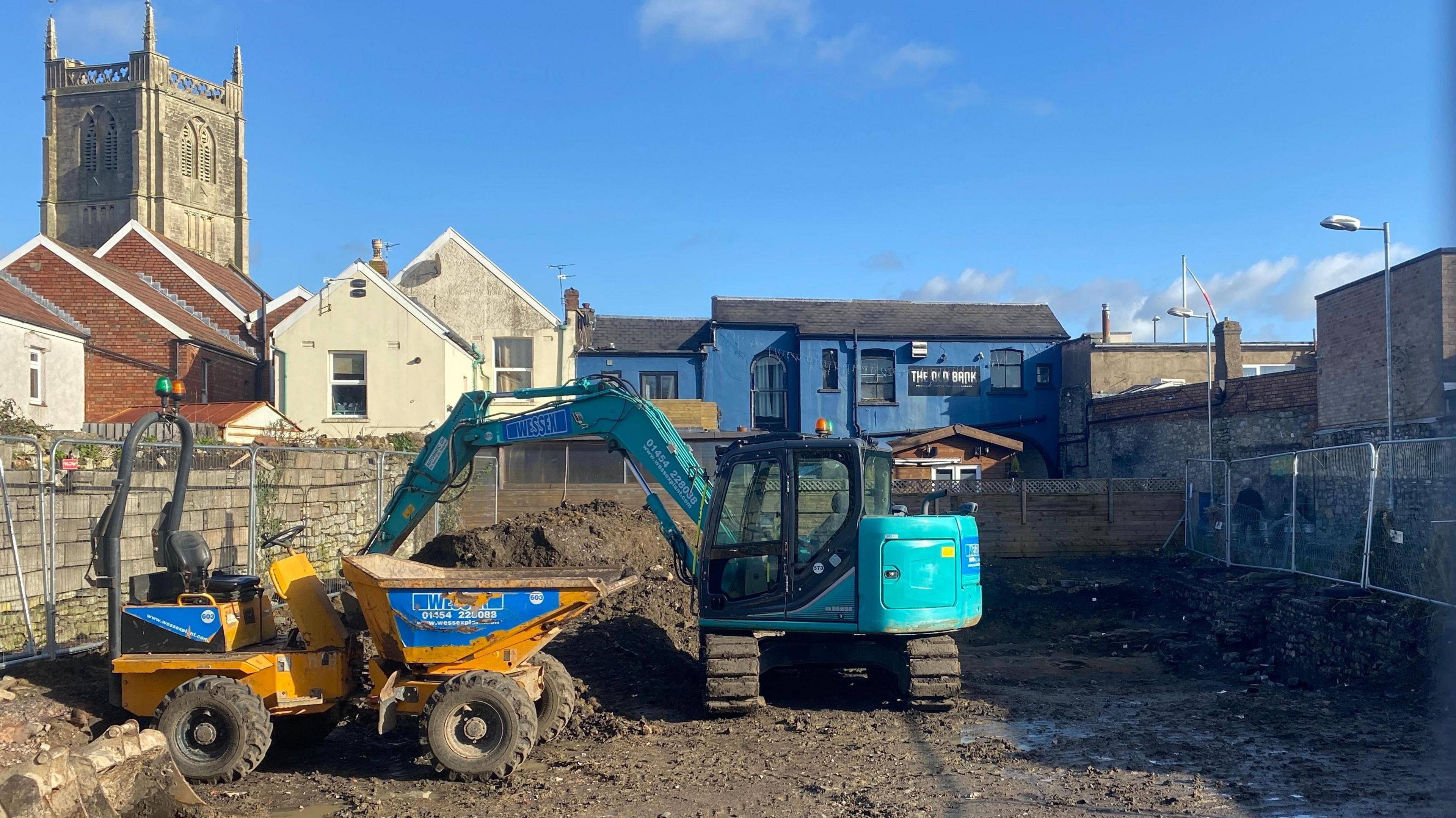 Construction site at Danes Lane in Keynsham. Construction vehicles and machinery can be seen in the site which is fenced off to the public.