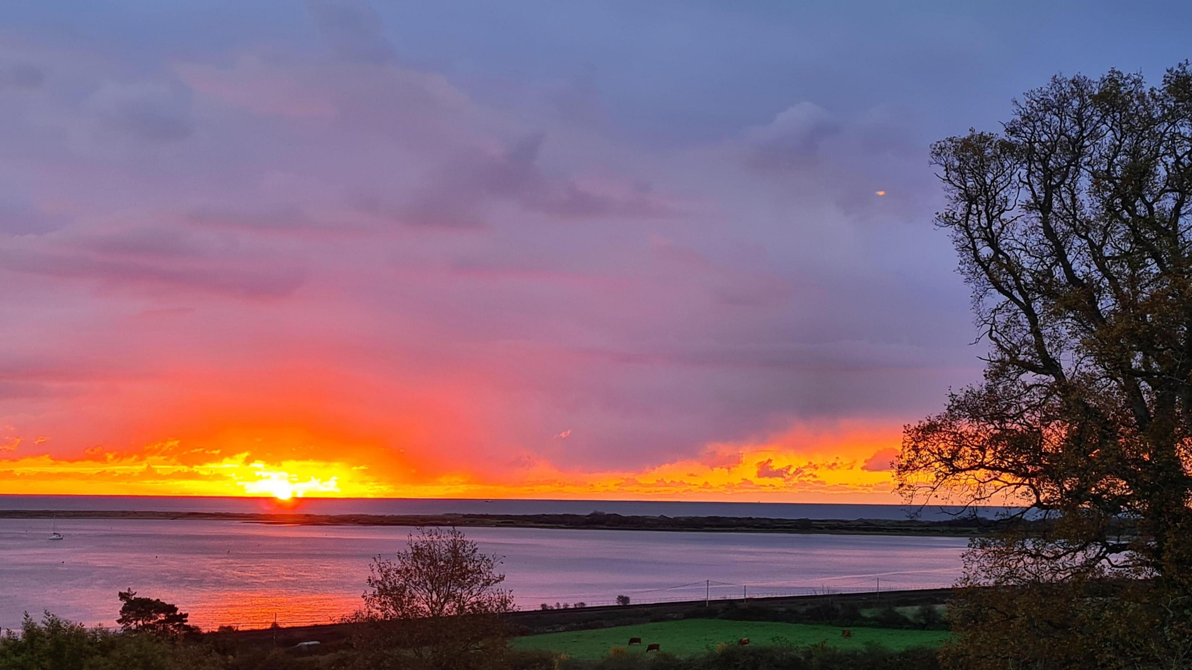 A sun is seen rising over a body of water in Starcross. 