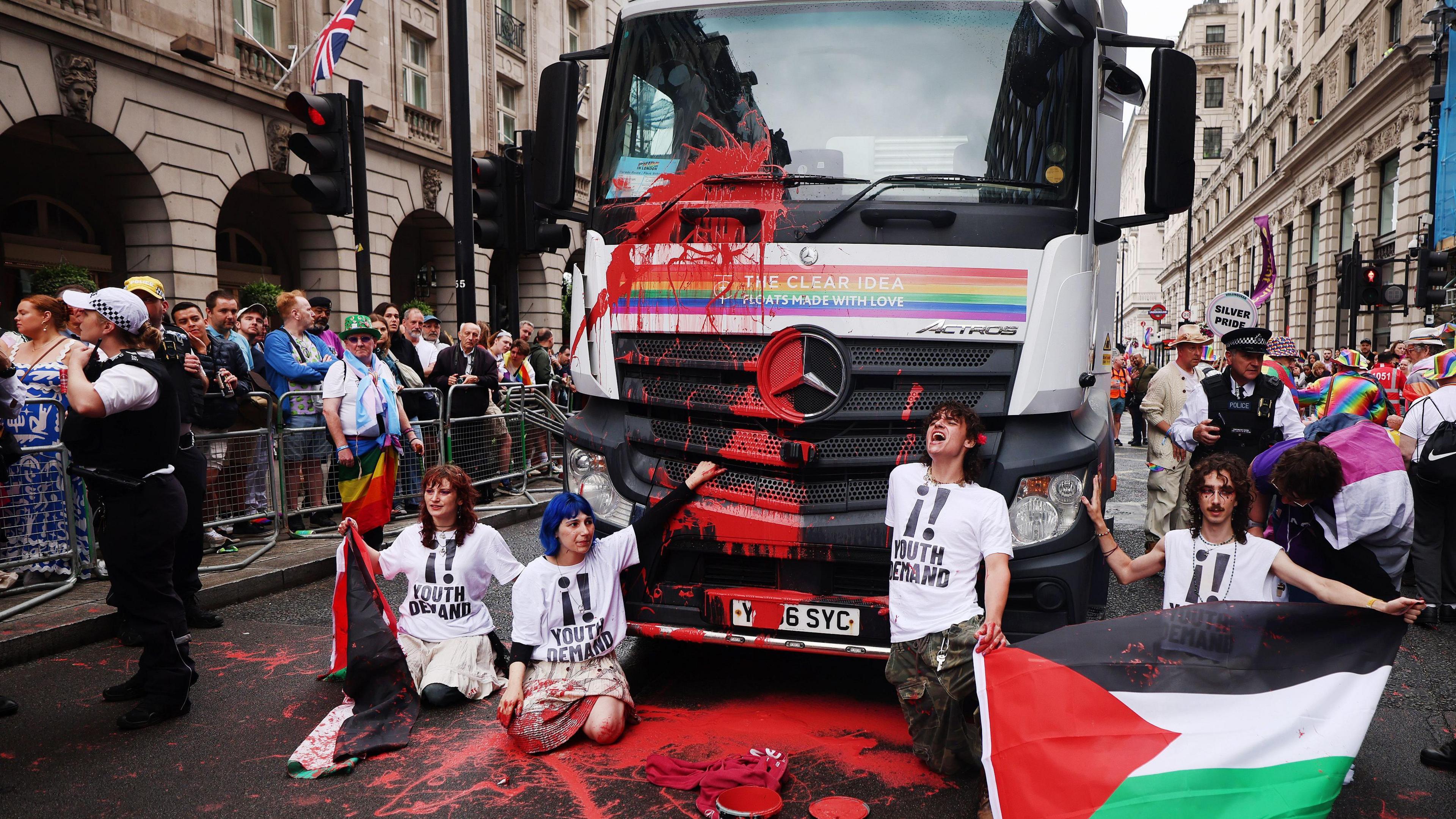 Pro-Palestine protesters from Youth Demand throw red paint and glue themselves to the lead float during the annual Pride parade.