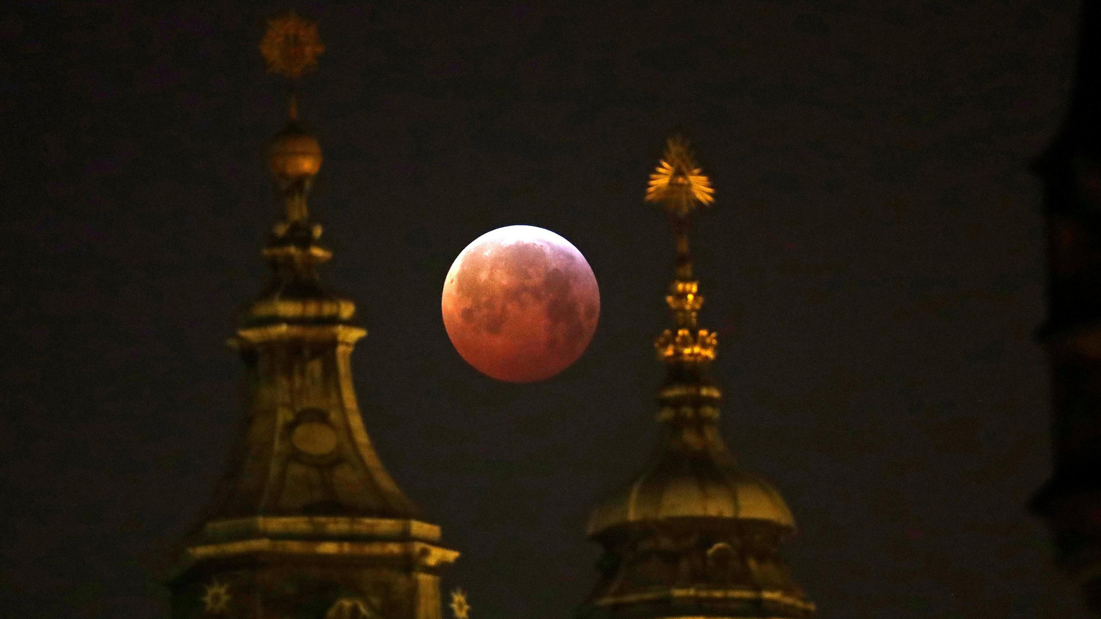 blood moon framed by two spires of a building in Prague