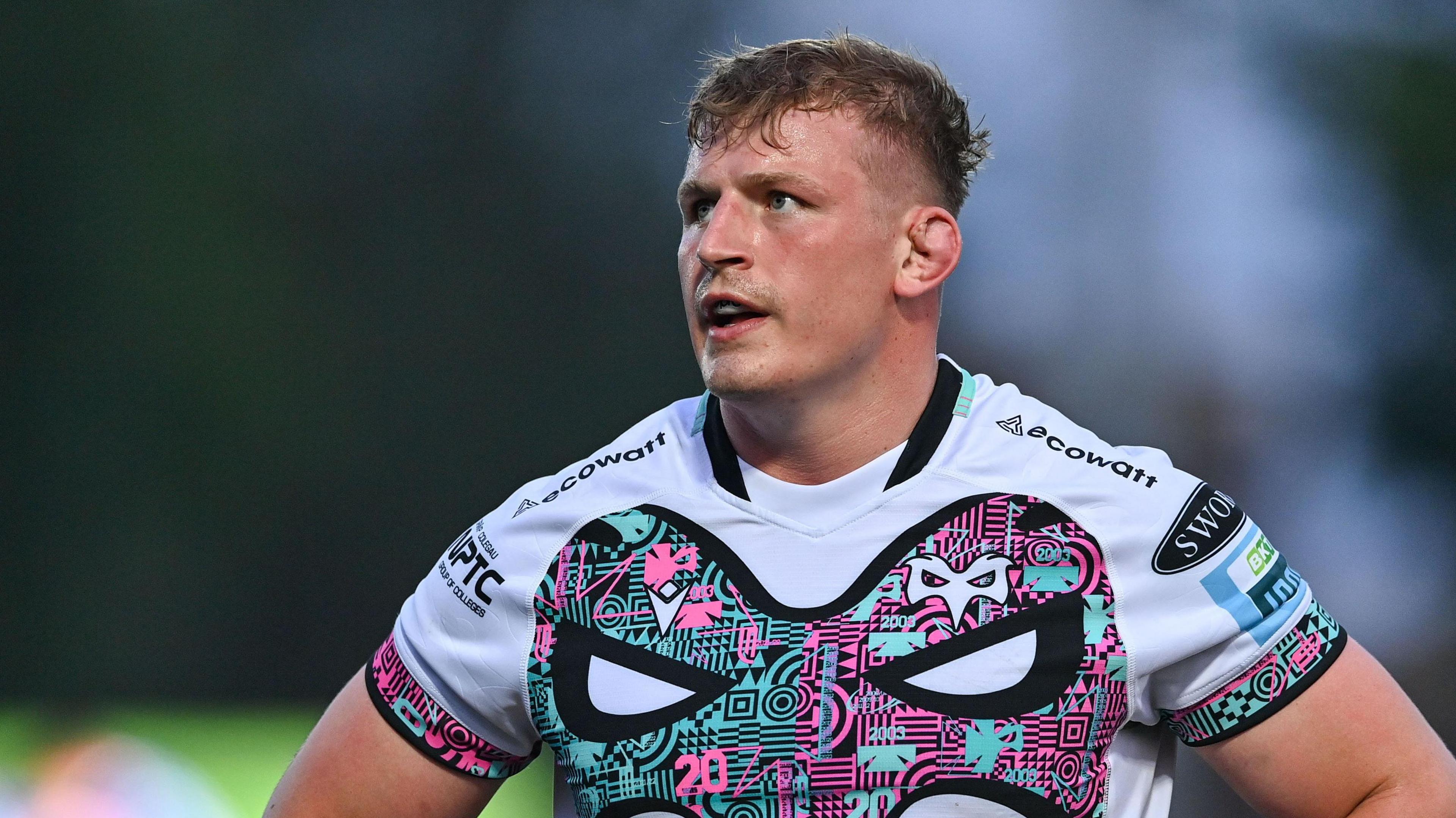 Jac Morgan wear a white rugby jersey with the black emblem of an osprey