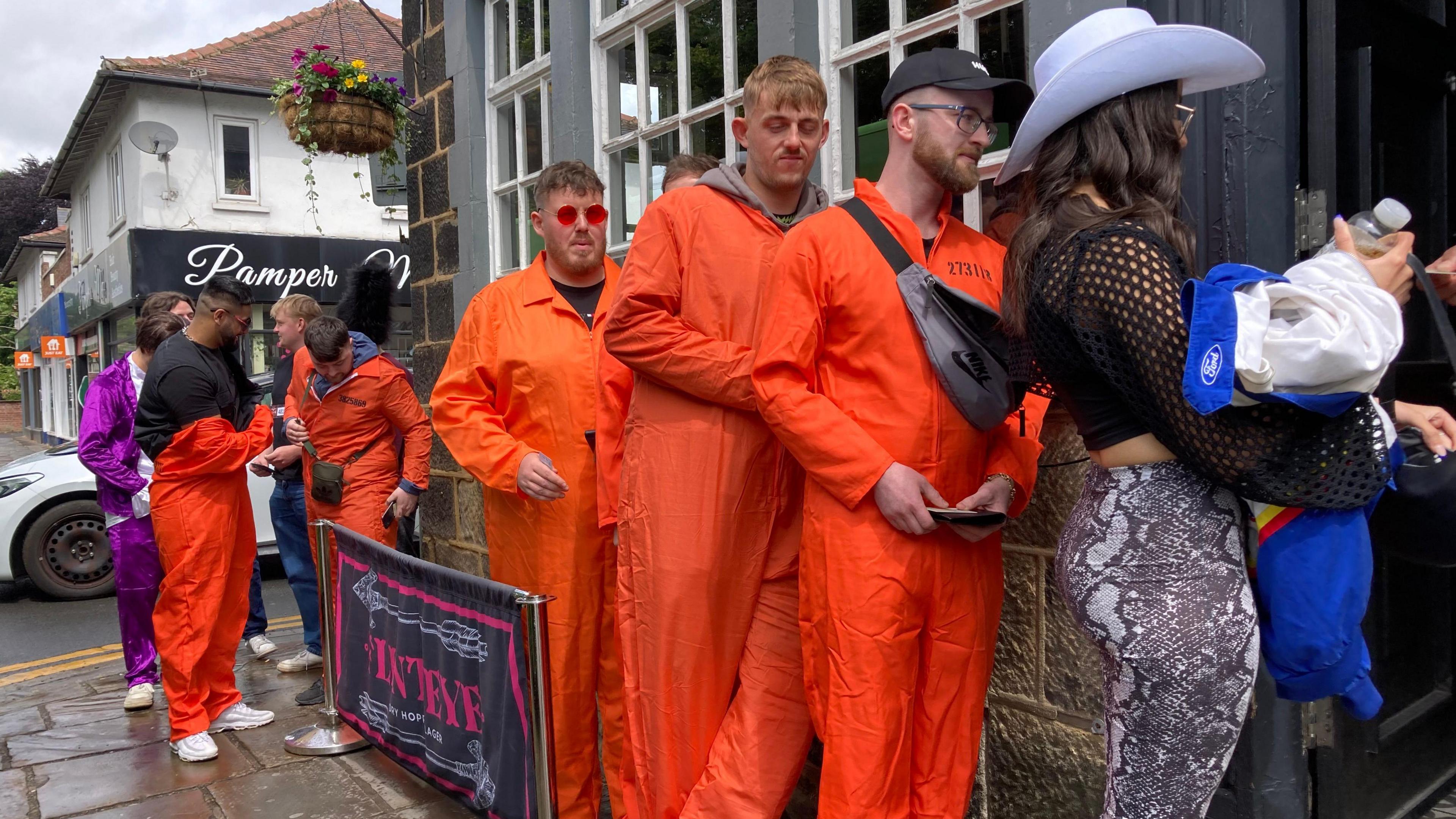 People wearing fancy dress queue to get in a pub