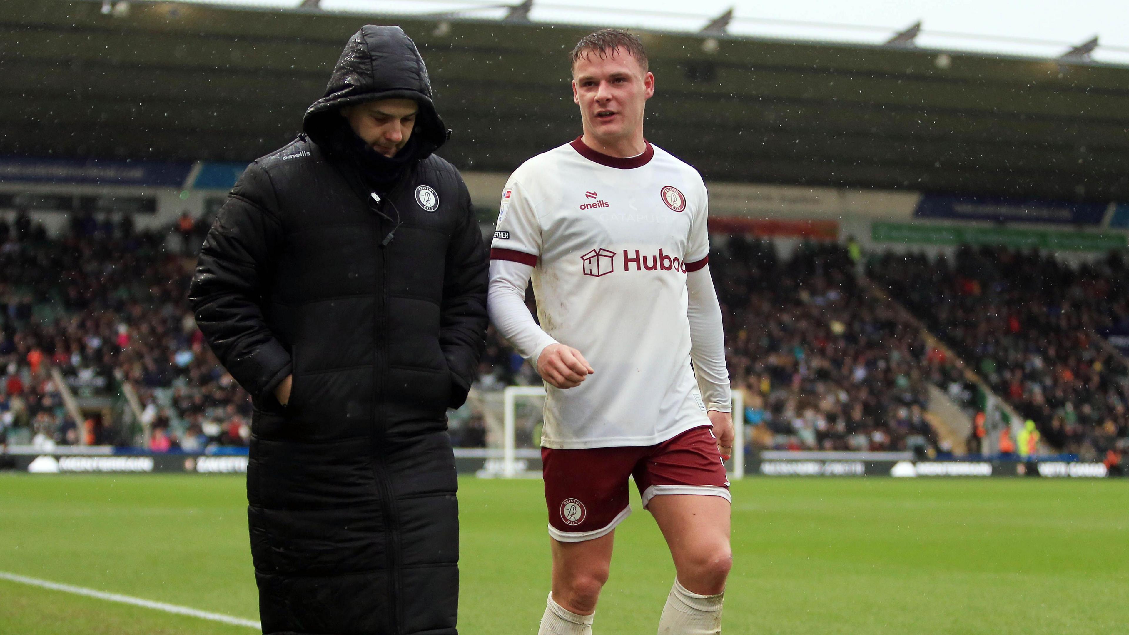 Cameron Pring (right) walks off the field with injury