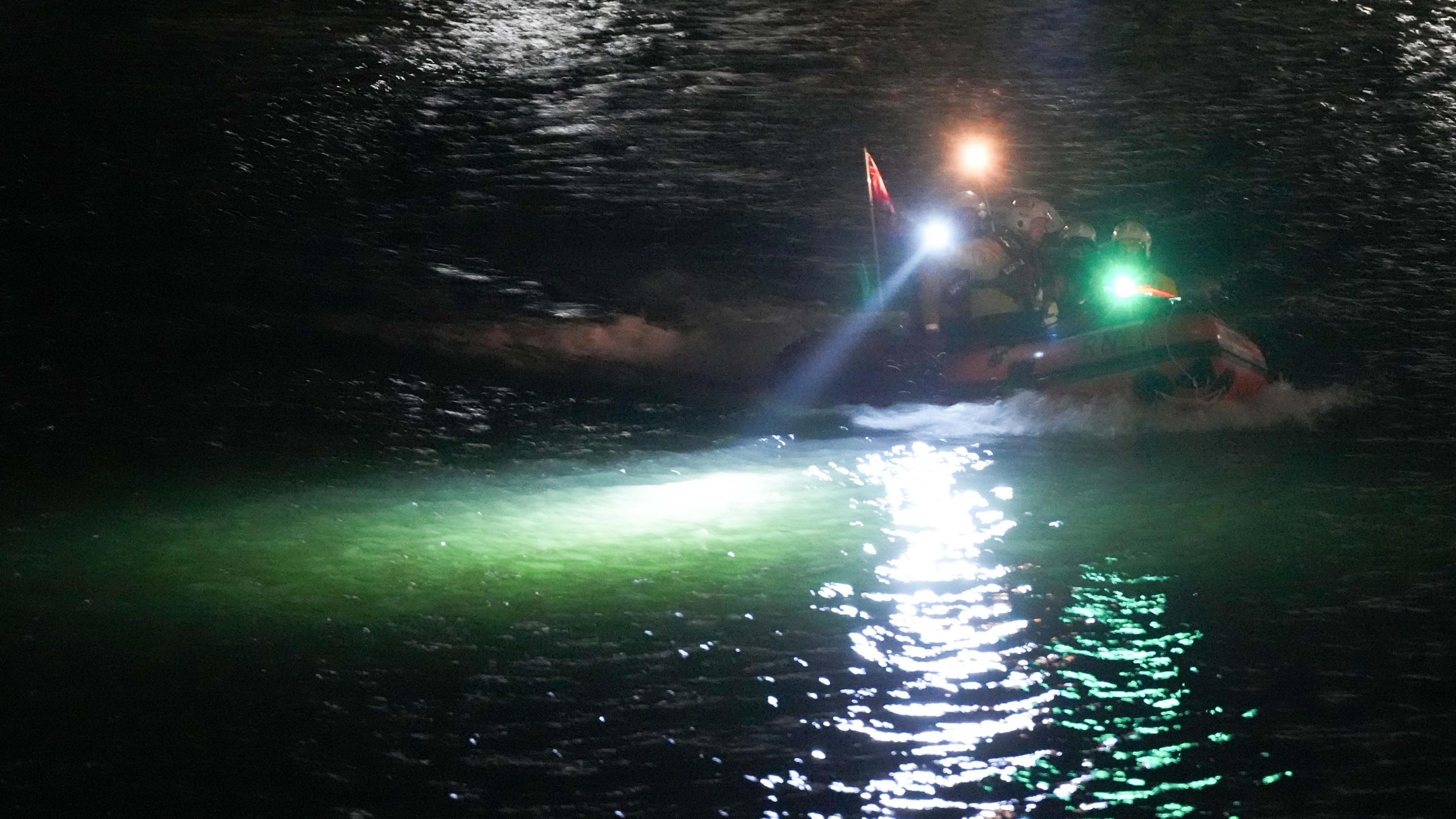 A boat in the river. Spotlights are lighting up the water. 