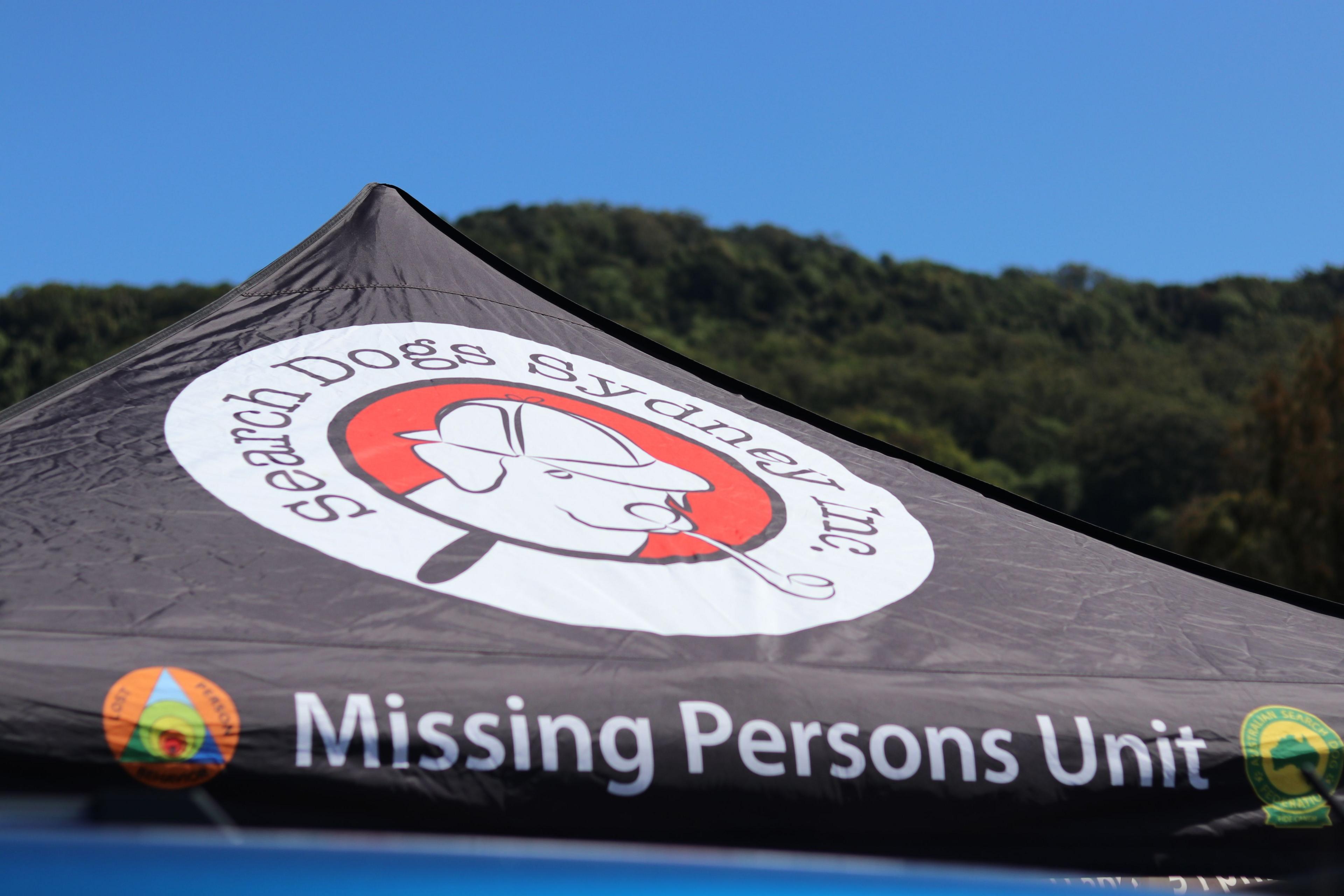 The top of a black tent reads Missing Persons Unit The top of a black tent reads Missing Persons Unit