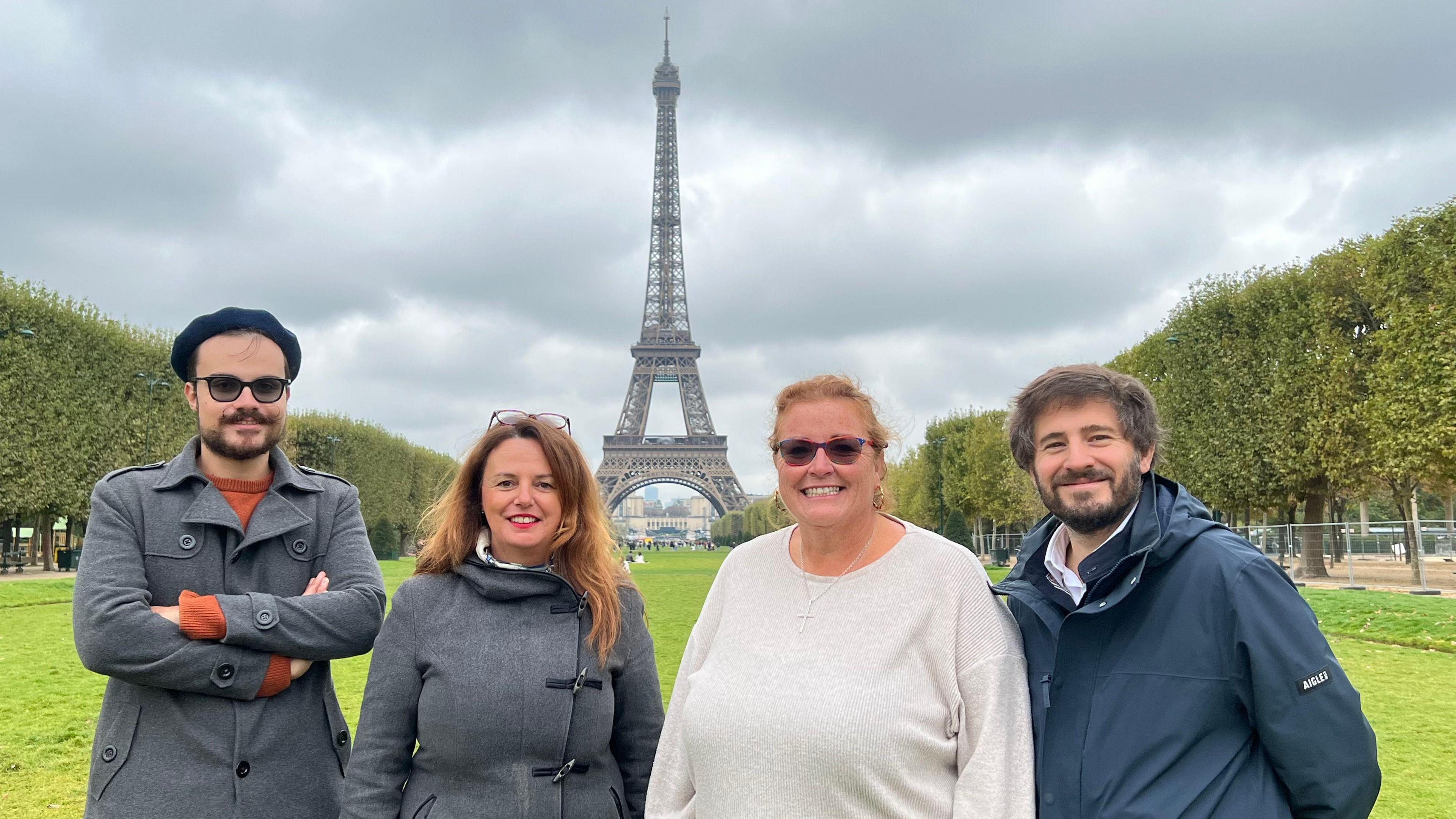 Two men and two women standing in front of the Eiffel Tower in France.