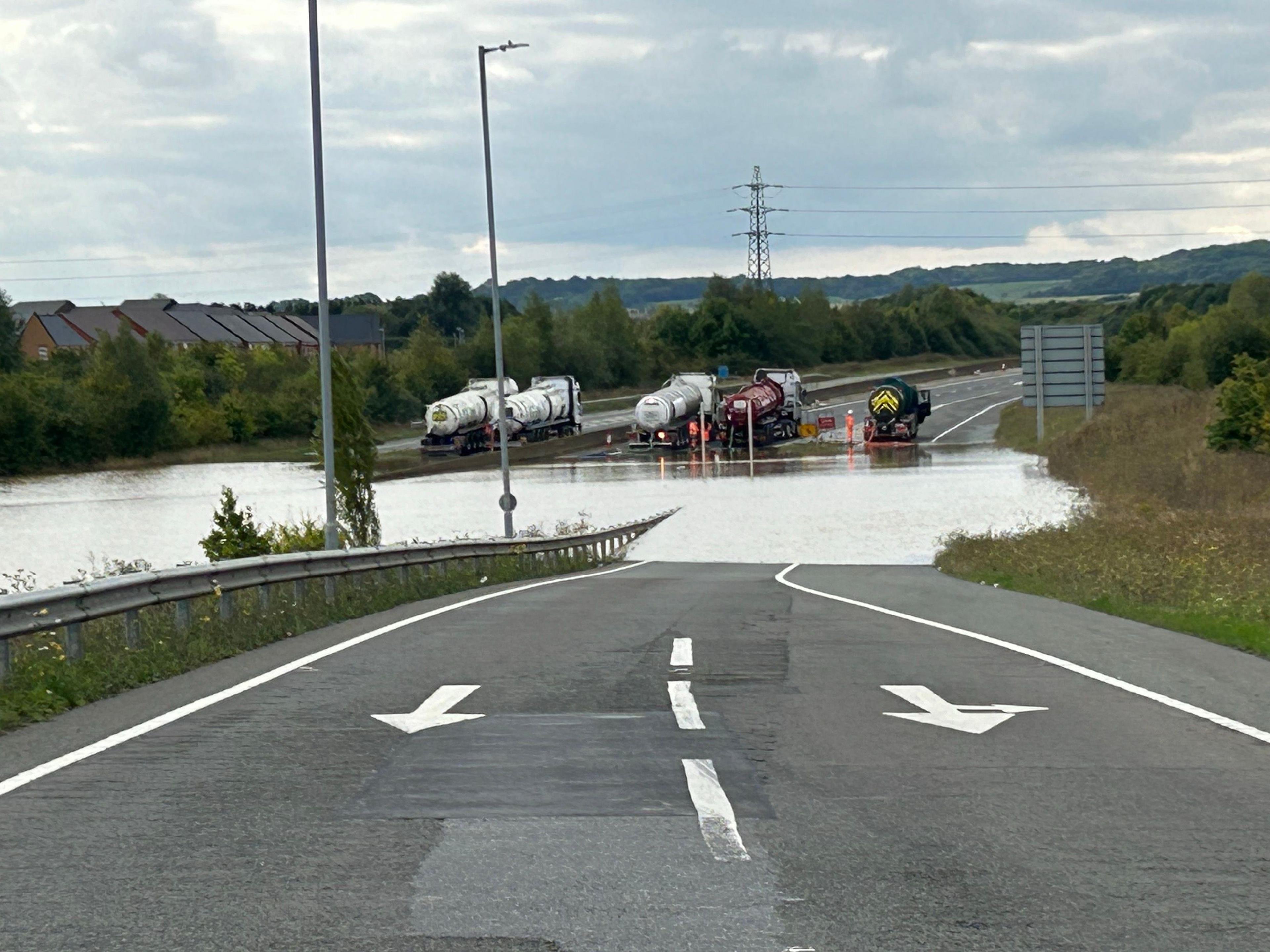 Five tankers are lined up across the A421 near Bedford and are pumping water from the carriageway