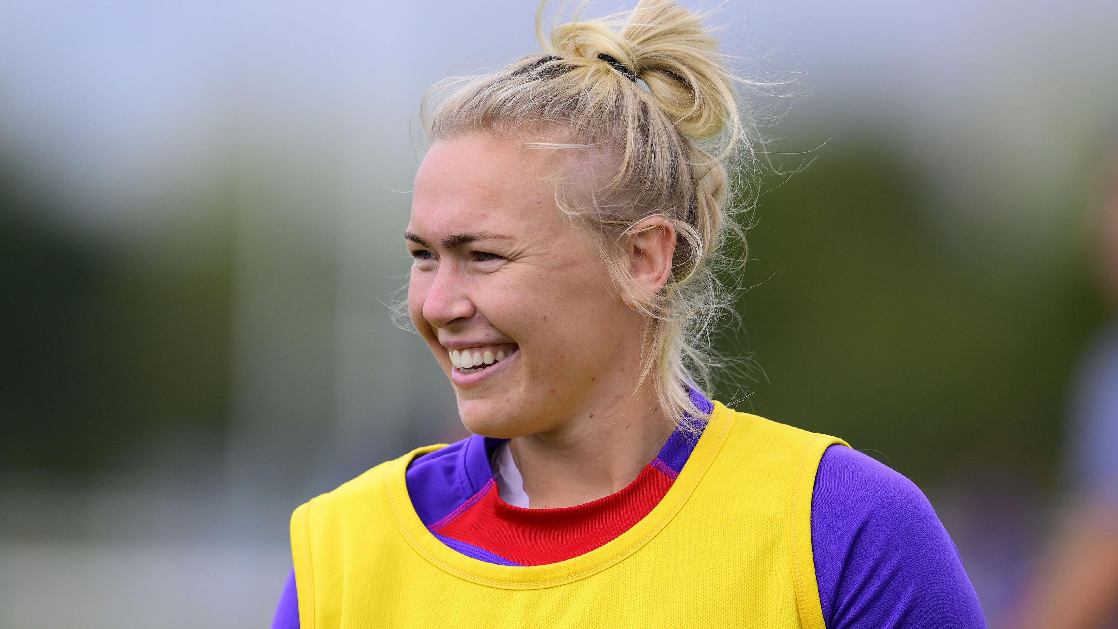 Rosie Galligan in purple England training top covered by yellow bib