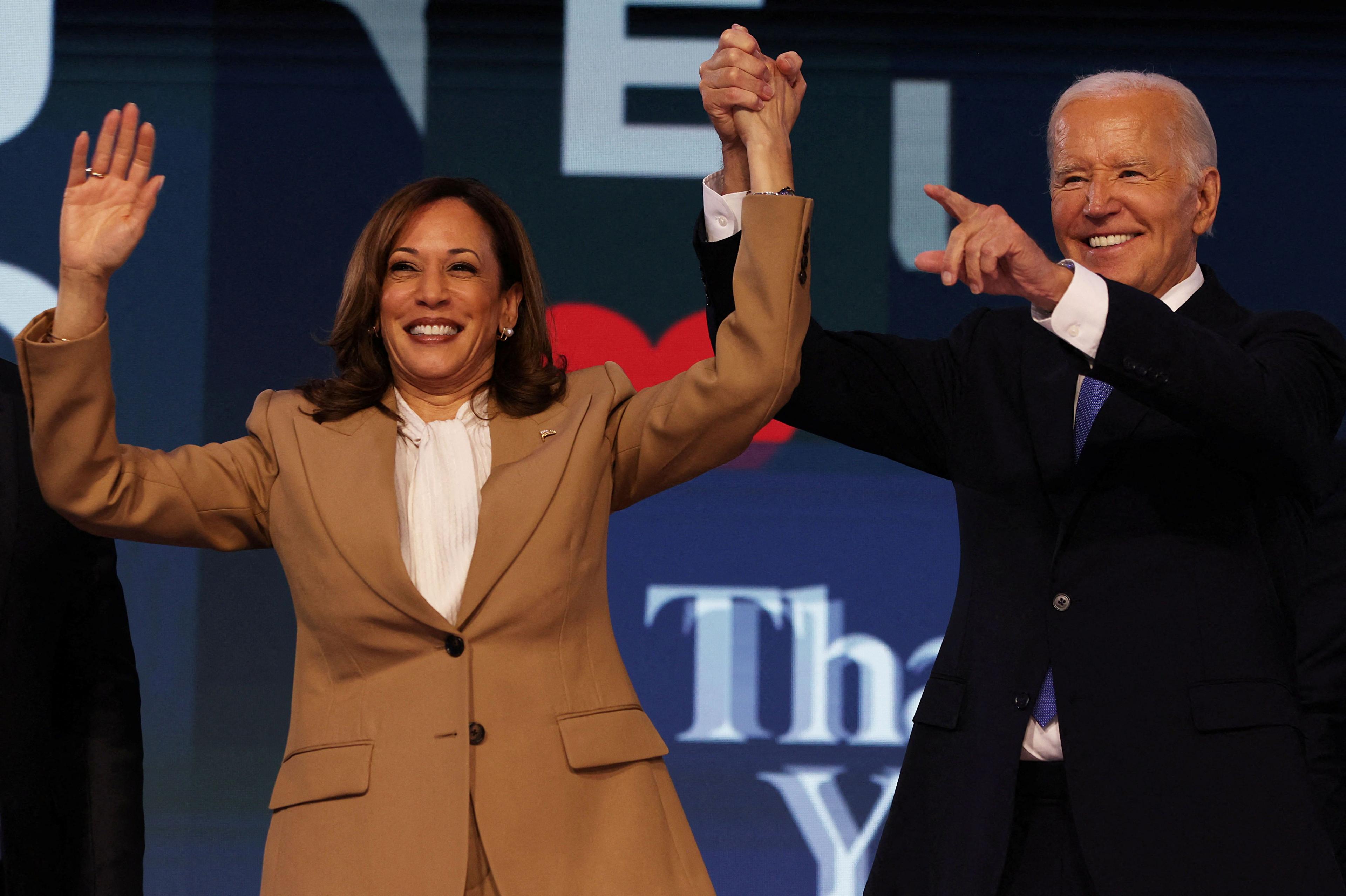 Joe Biden holds Kamala Harris' hand in the air while gesturing at Day One of the Democratic National Convention