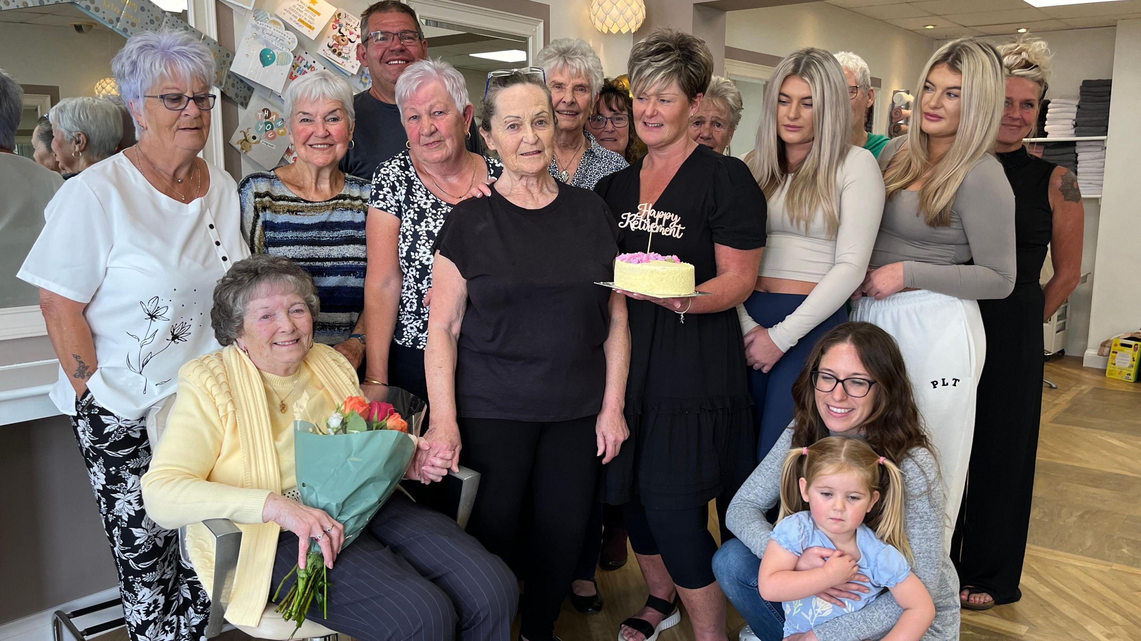 Sandra Handel on her last day at work at her salon in Highbridge. Customers, colleagues, friends and family have gathered around her to wish her well and one of them is holding a cake