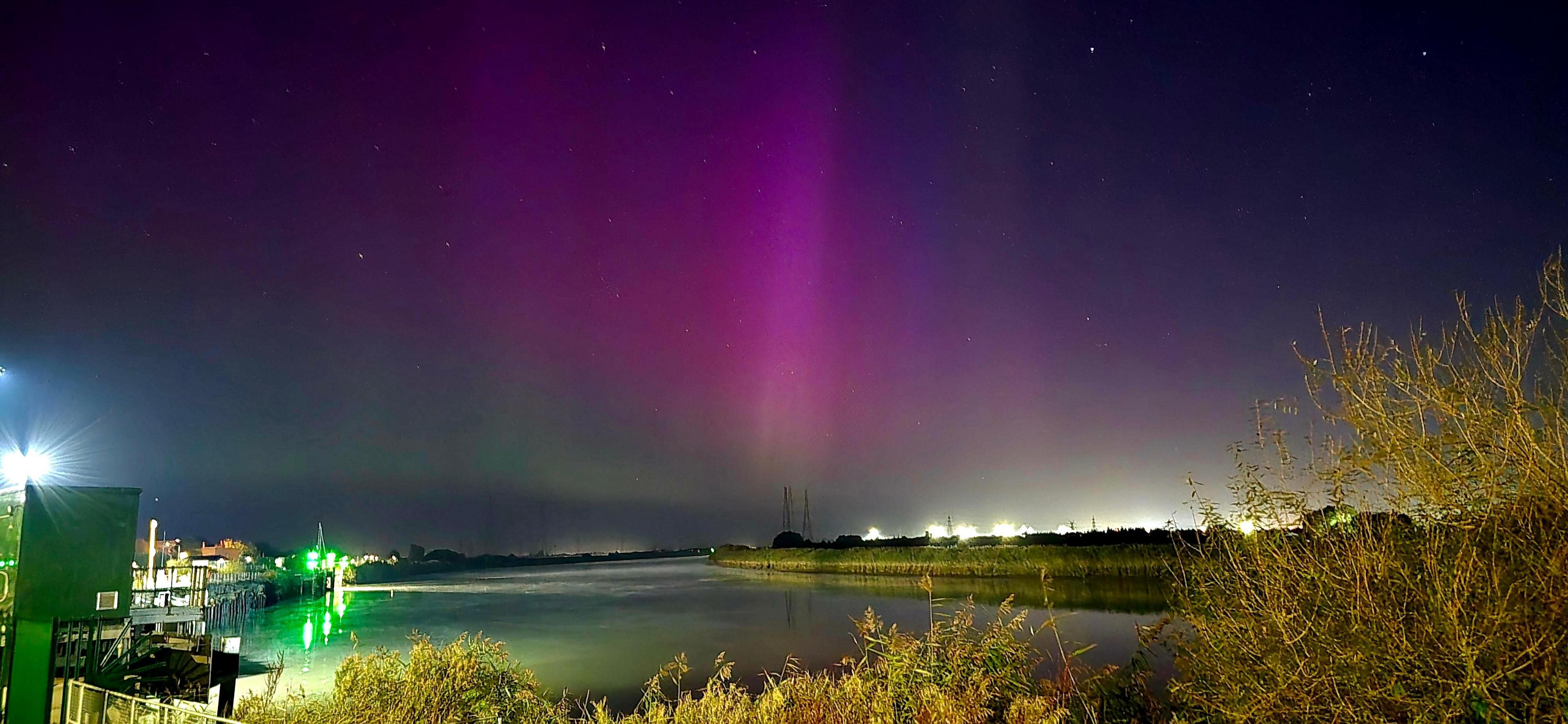 River Trent at Keadby lit by lights from buildings,  with the green and purple of the Northern Lights in the sky