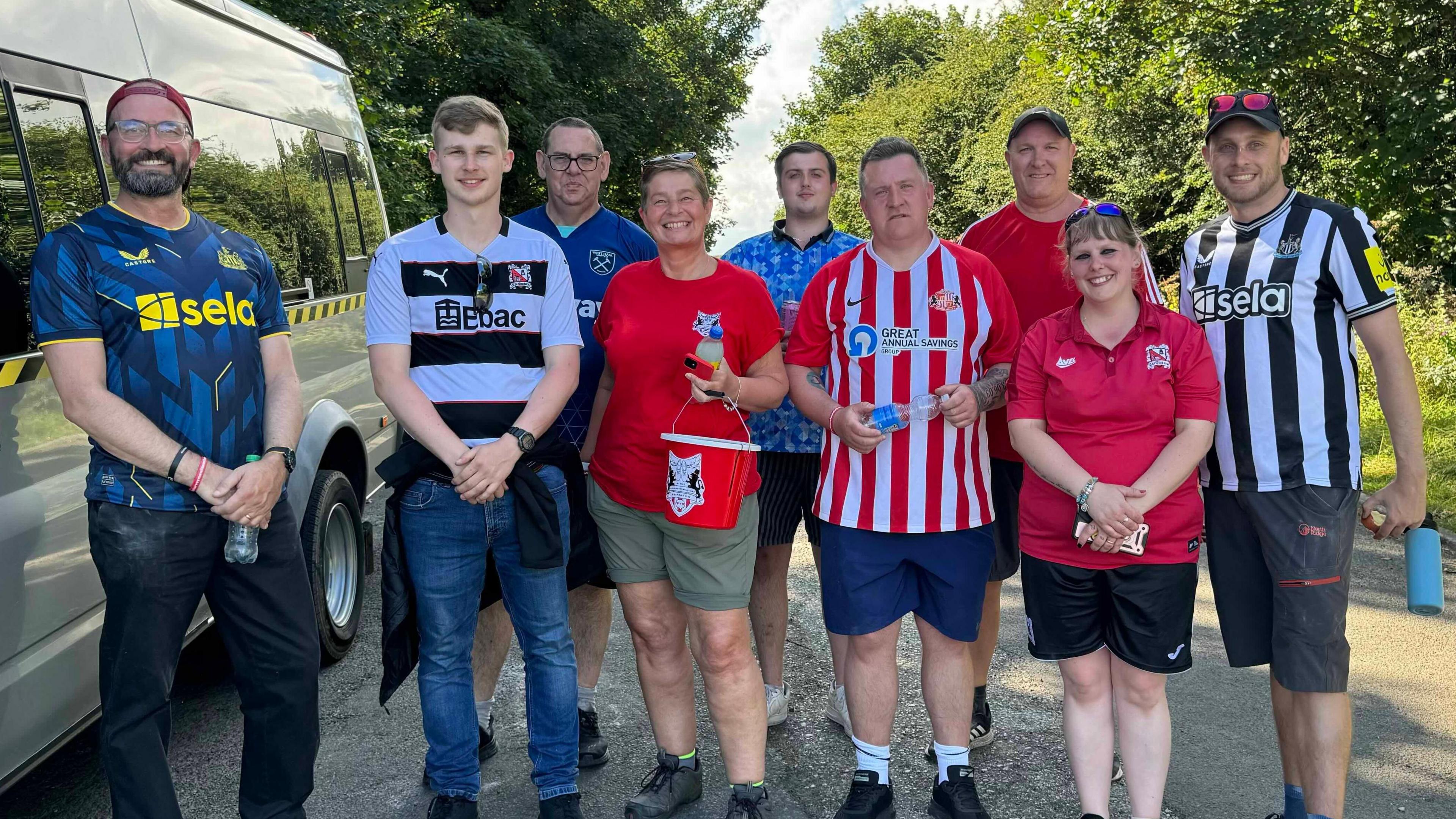 A group of walkers on a woodland path dressed in football shirts