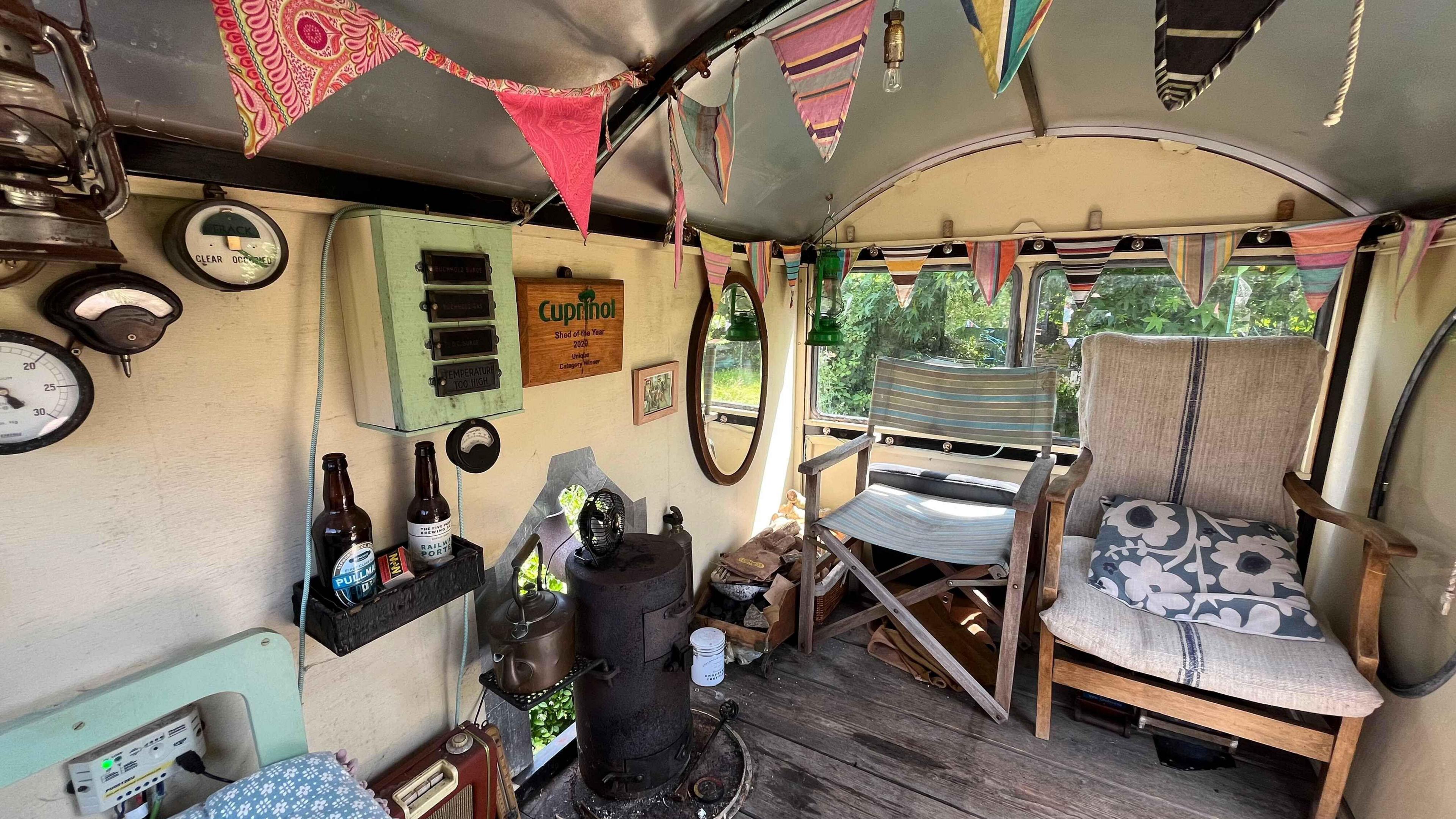 Four seats inside Adrian's cabin and a wood burning stove. There is also bunting and more original train memorabilia 