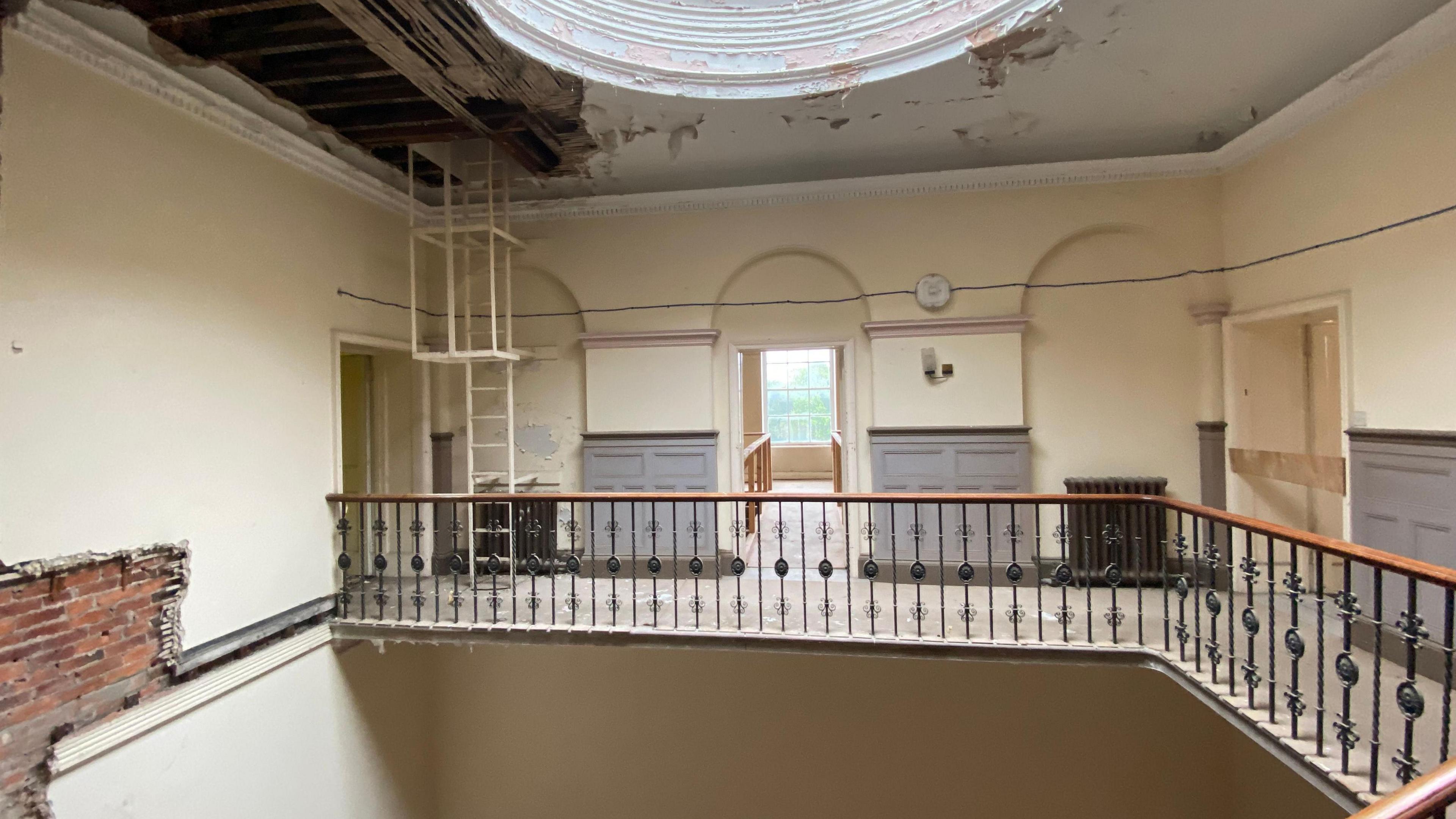 View of the inside stairwell which has exposed brick and peeling plaster