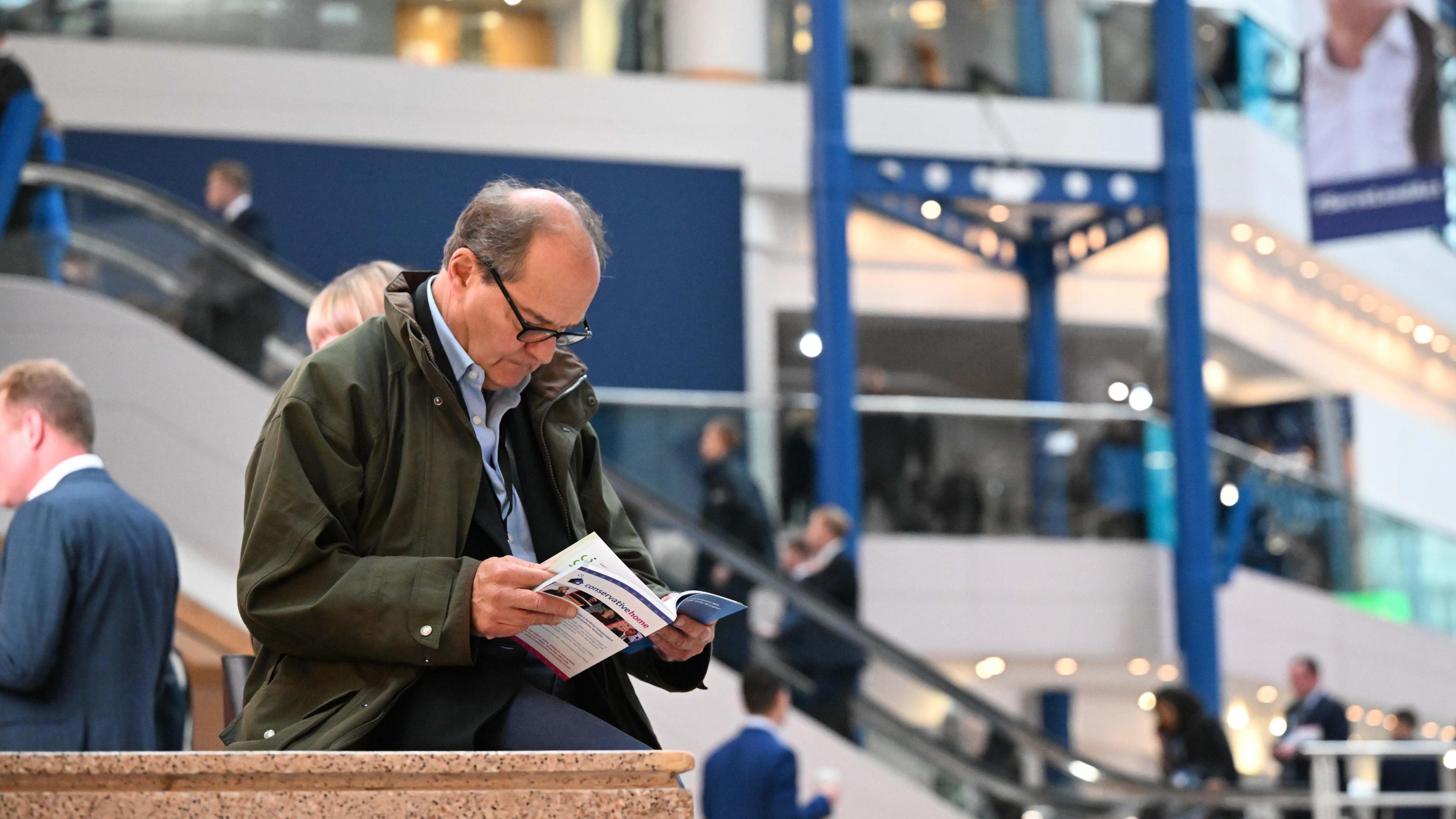 A delegate at the Conservative party conference reading the conference agenda